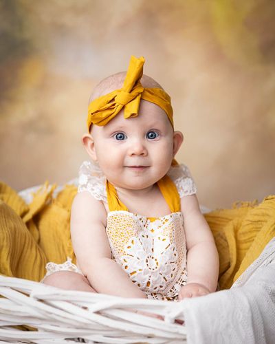 baby på 6 måneder med gul body med gul bakgrunn.Babyfotografering i studio på Fjerdingby på Romerike