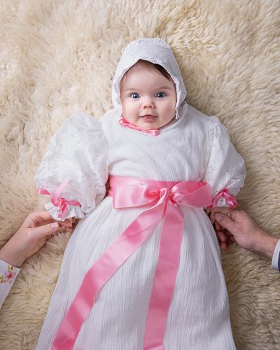 Baby i dåpskjole med rosa sløyfe. Babyfotografering i studio på Fjerdingby på Romerike