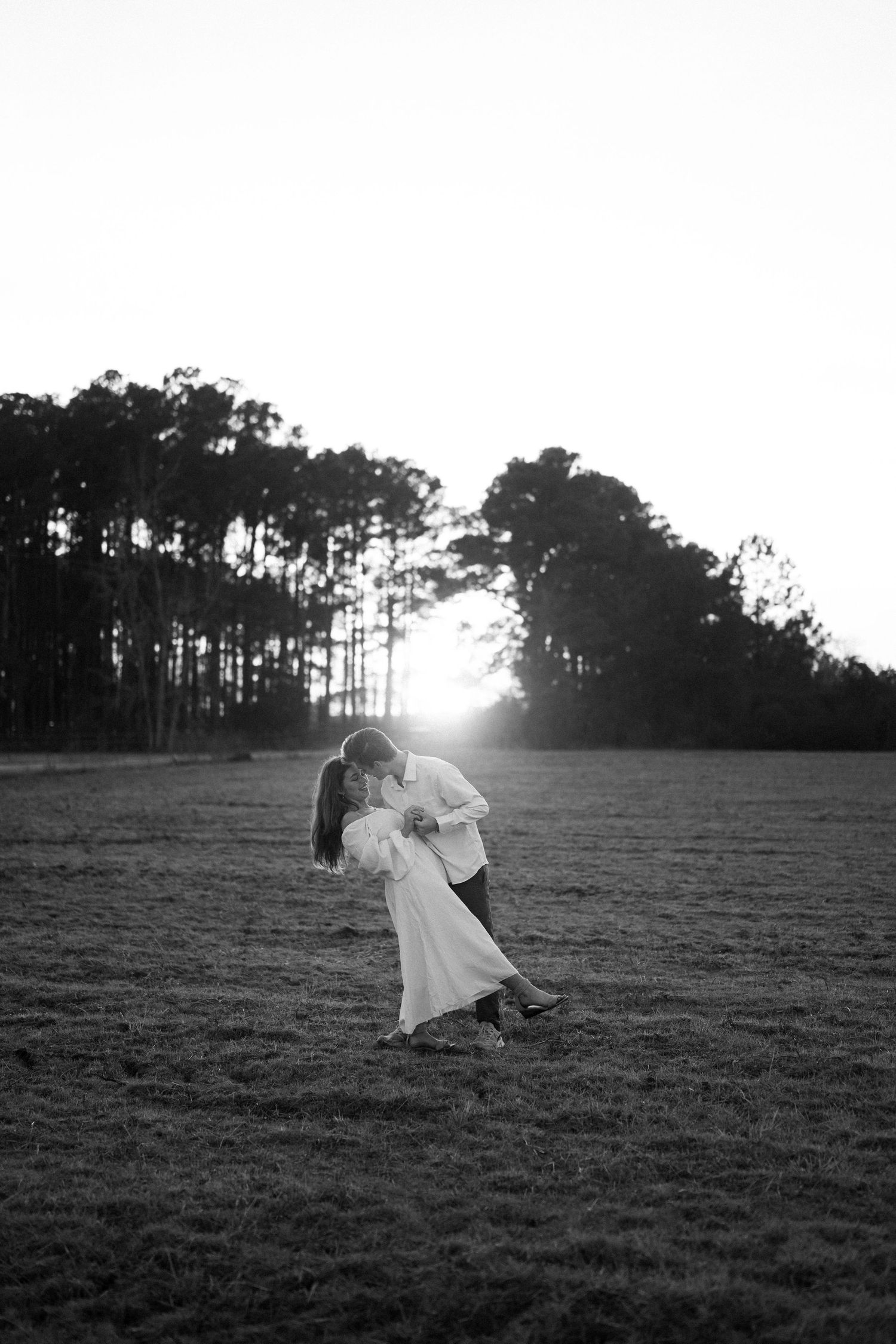 A person in white stands with their dog near a beach fence while tall grass sways in the coastal breeze.