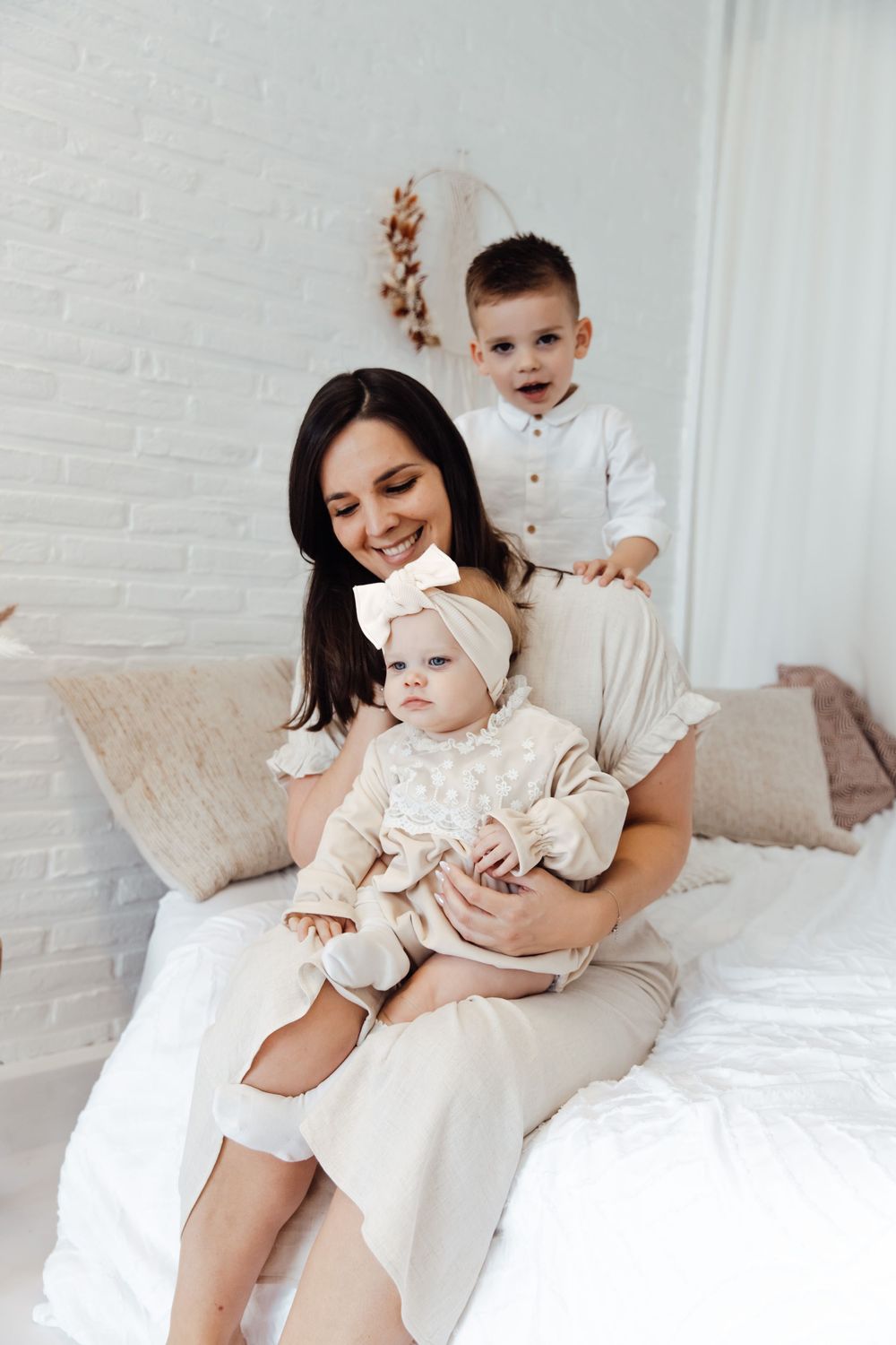 A family enjoying a cozy moment together while sitting on a white bed in a bright minimalist room.