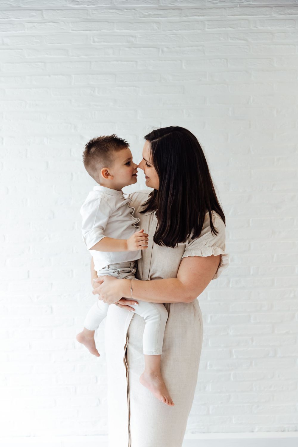 A tender moment shared between parent and child in white outfits against a light background.