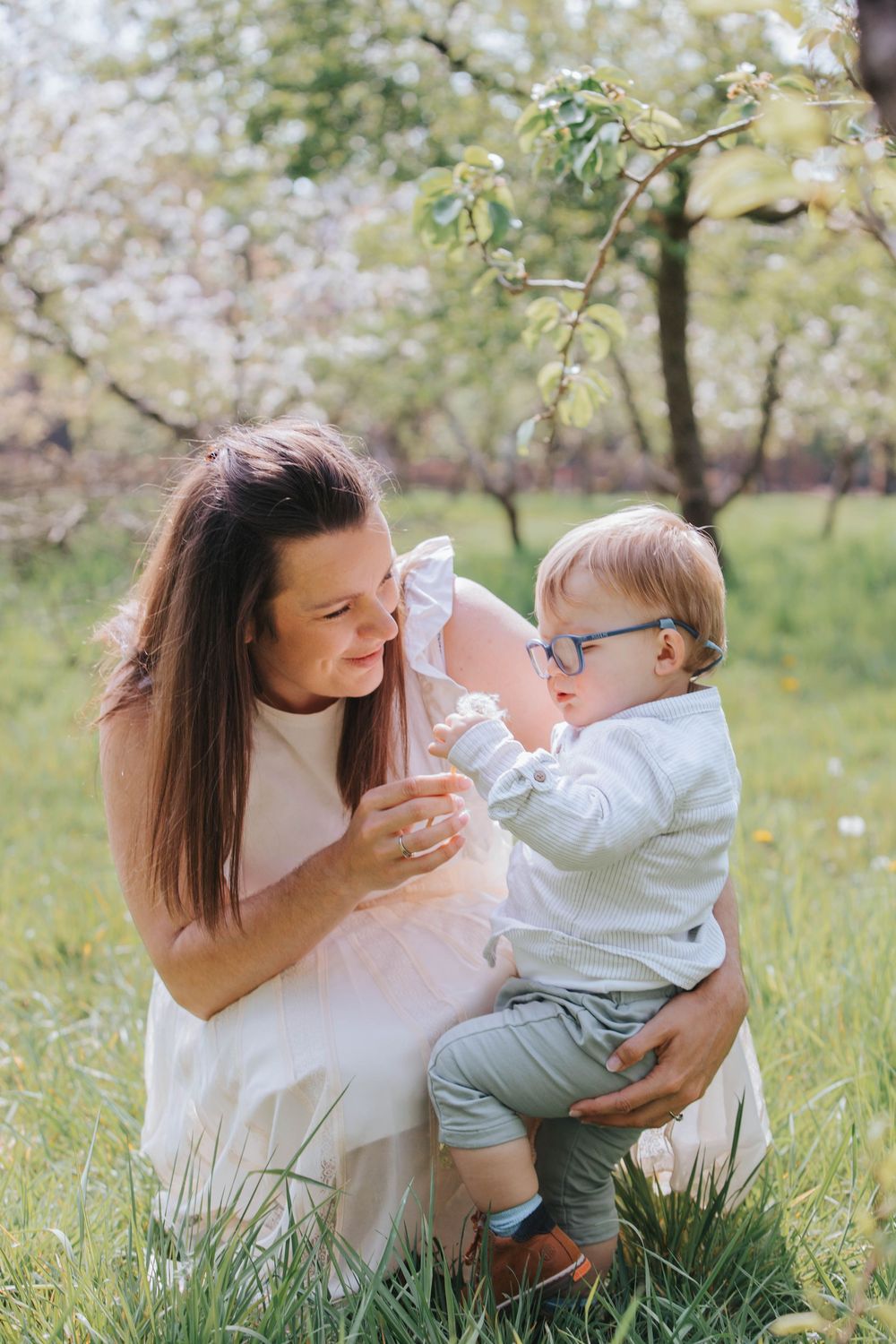 A tender moment between parent and child as they laugh and play together in a blooming spring orchard.