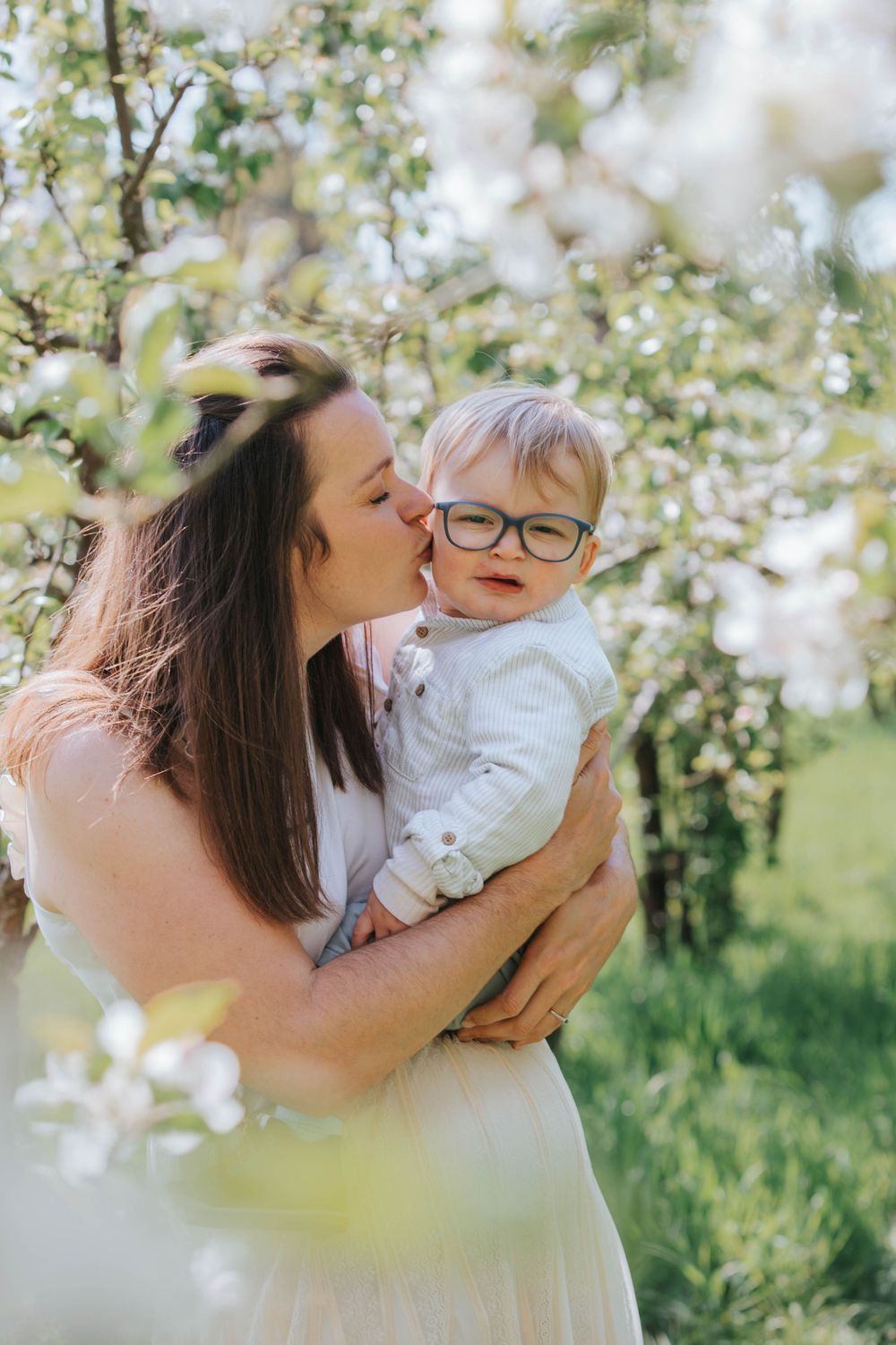 A tender spring moment captured outdoors among blooming trees and soft natural light.