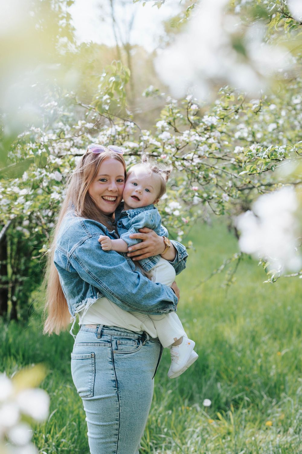 A joyful moment captured outdoors with blooming spring flowers and apple blossoms in a sunny garden setting.