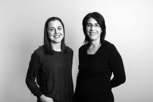 Professional headshot of two colleagues in black attire against white background.