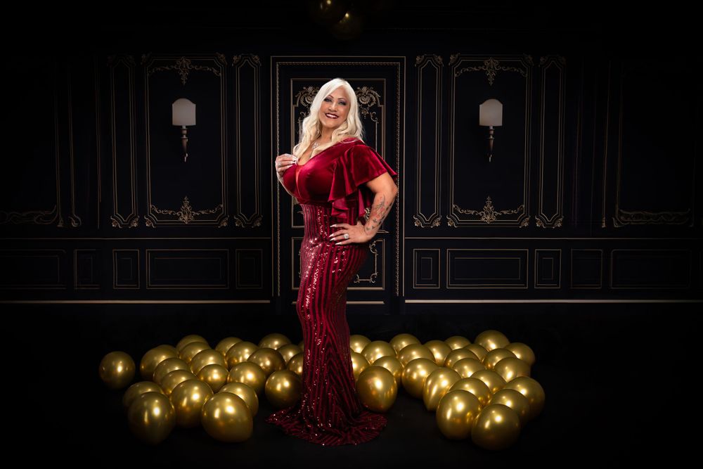 Full length evening portrait with red sequined gown and gold balloon decorations.