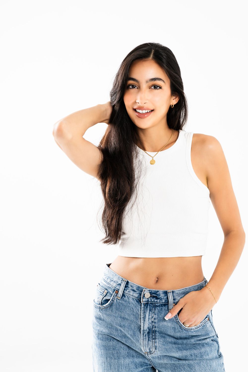 Model in white crop top and baggy jeans poses against white studio backdrop.