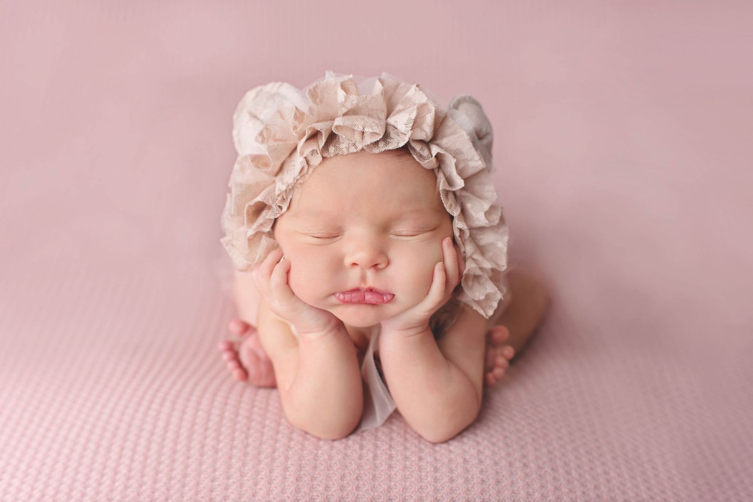newborn baby girl in froggy pose on pink backdrop with bear bonnet