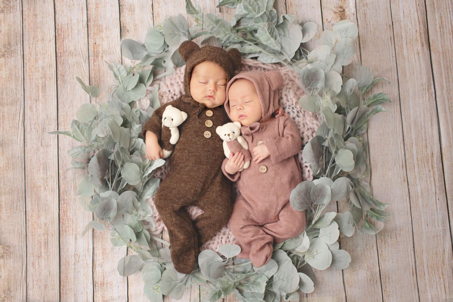 boy girl newborn twins with green foliage and bear outfits on wood backdrop