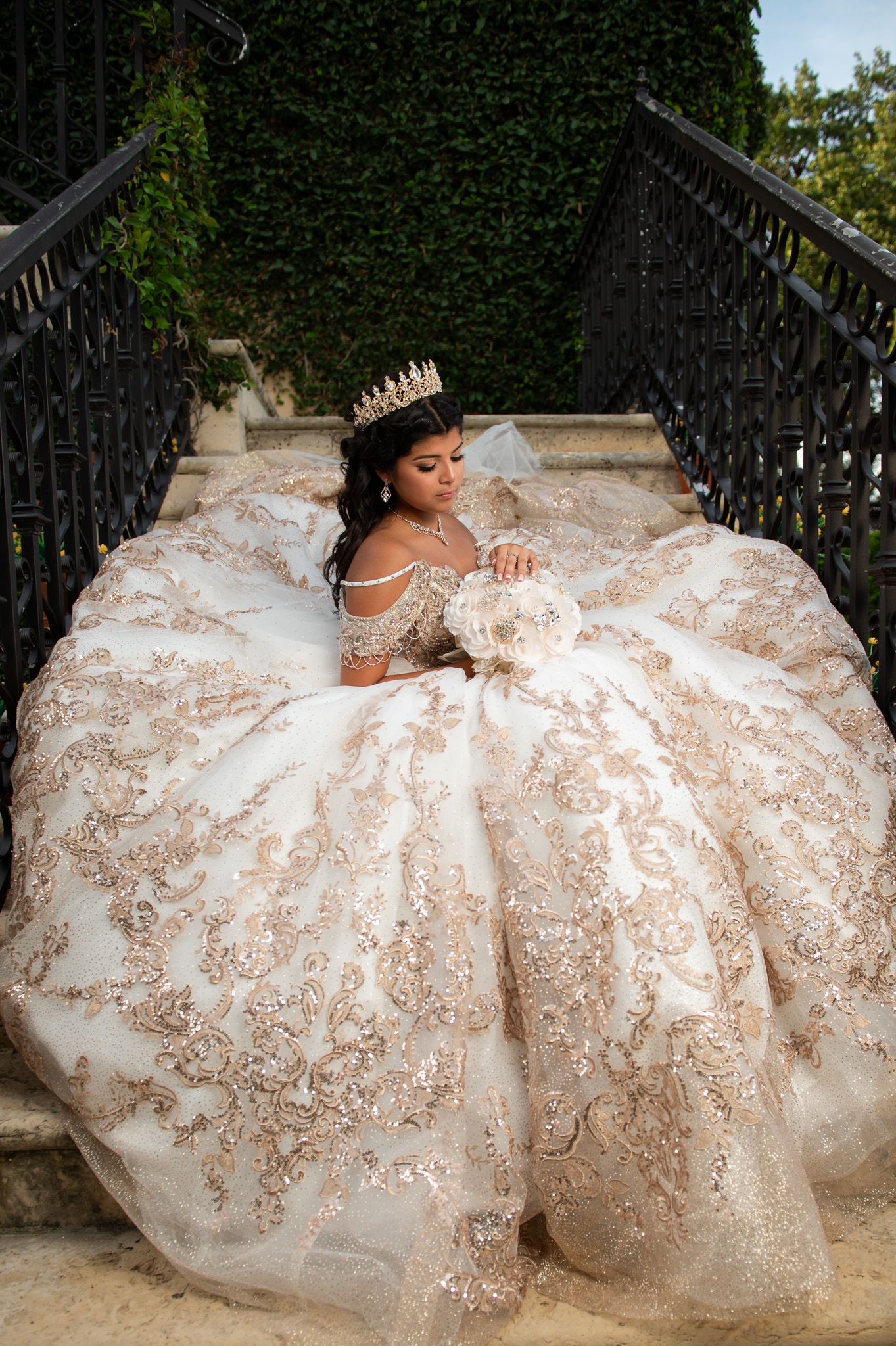 An ornate white wedding gown with detailed beadwork spreads across stone steps.
