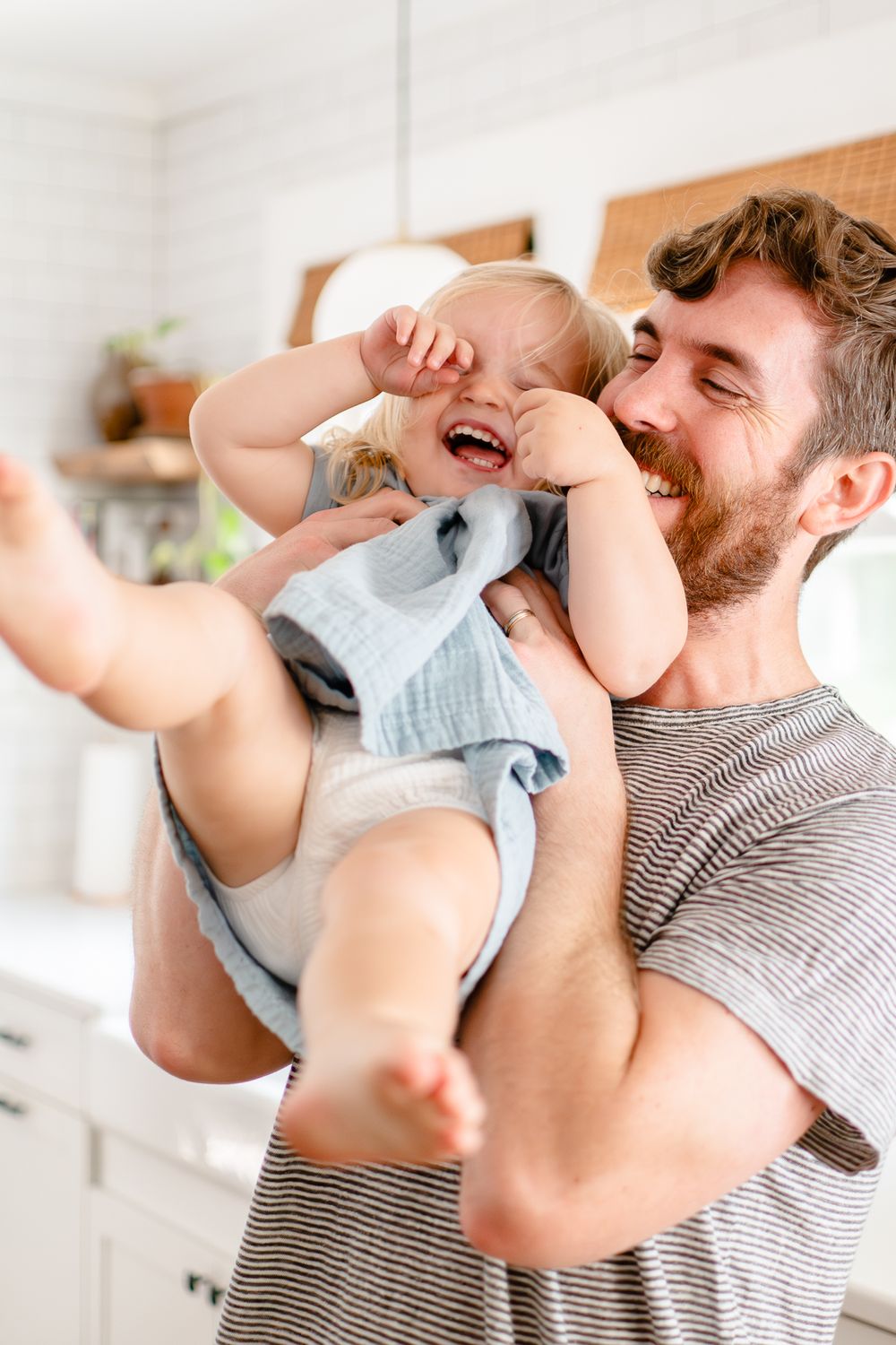 Dad lifts little girl into the air and giggle ensue during family photos.