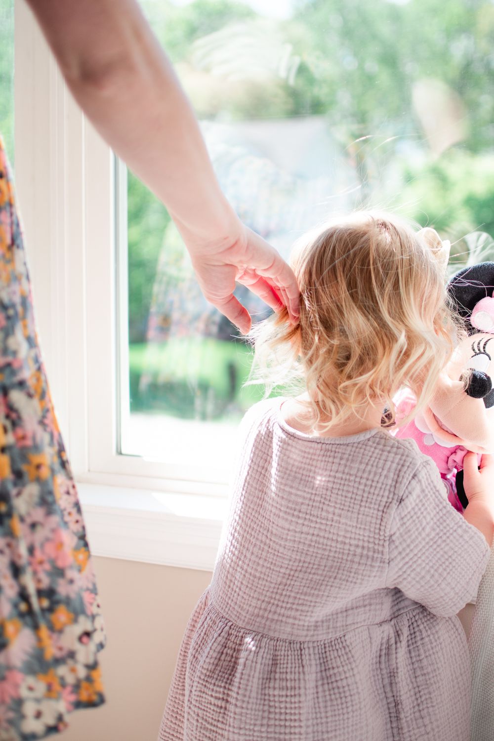 Mom brushes daughter's hair in a tender moment at their family home.