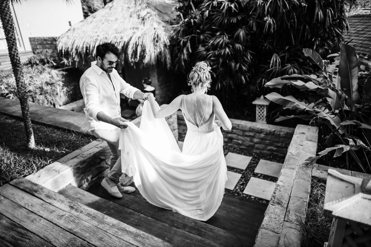 A black and white photo of a couple on a wooden deck surrounded by tropical plants.