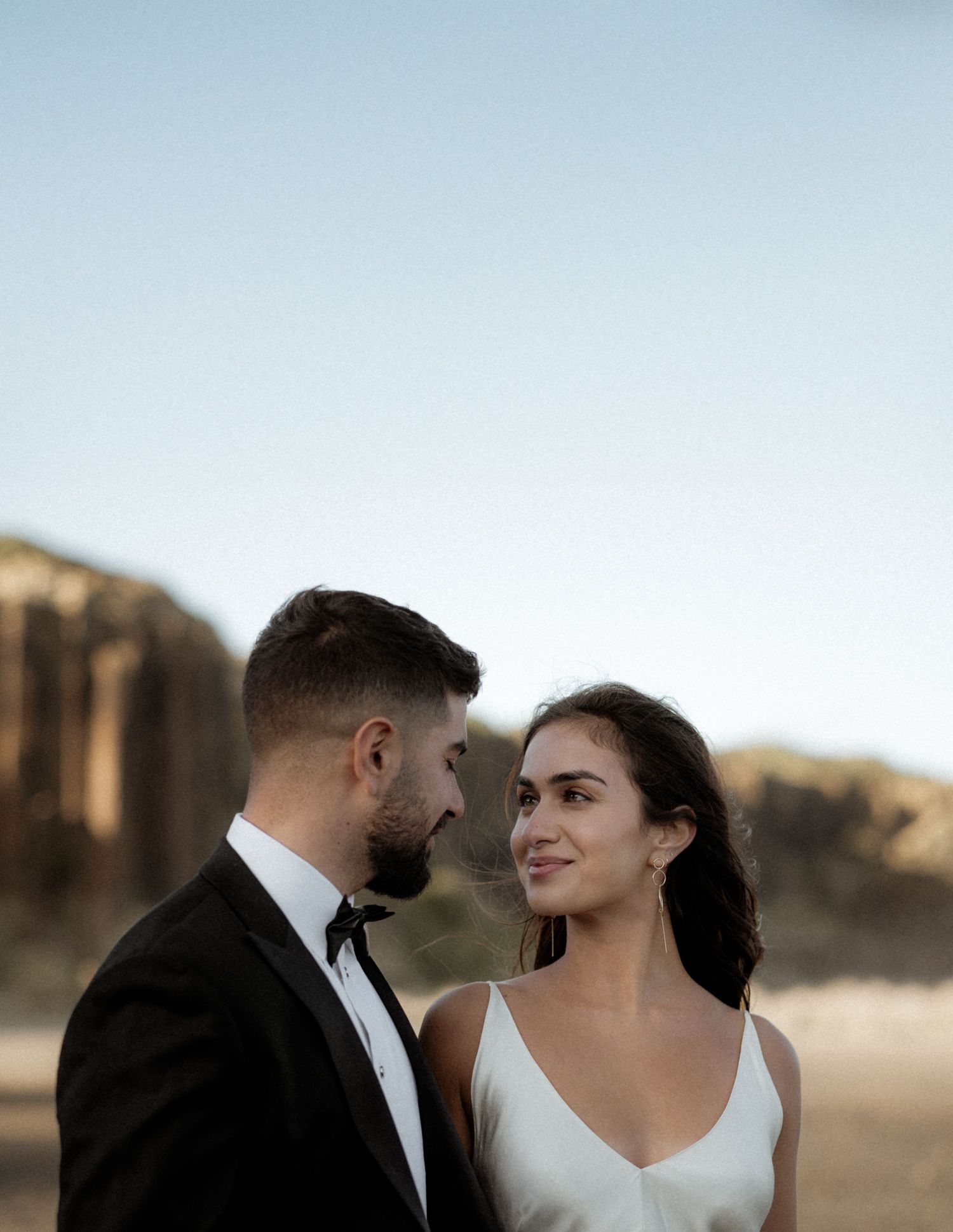 Close-up of couple sharing intimate moment against stunning cliff backdrop.