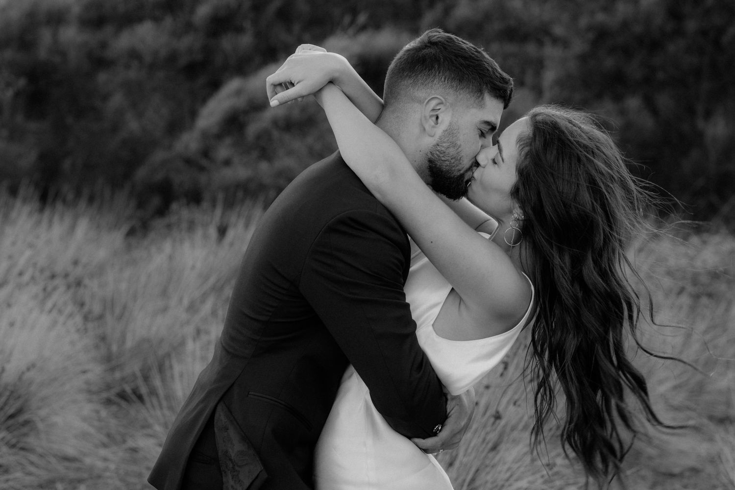 Black and white portrait of romantic wedding couple sharing intimate moment outdoors.