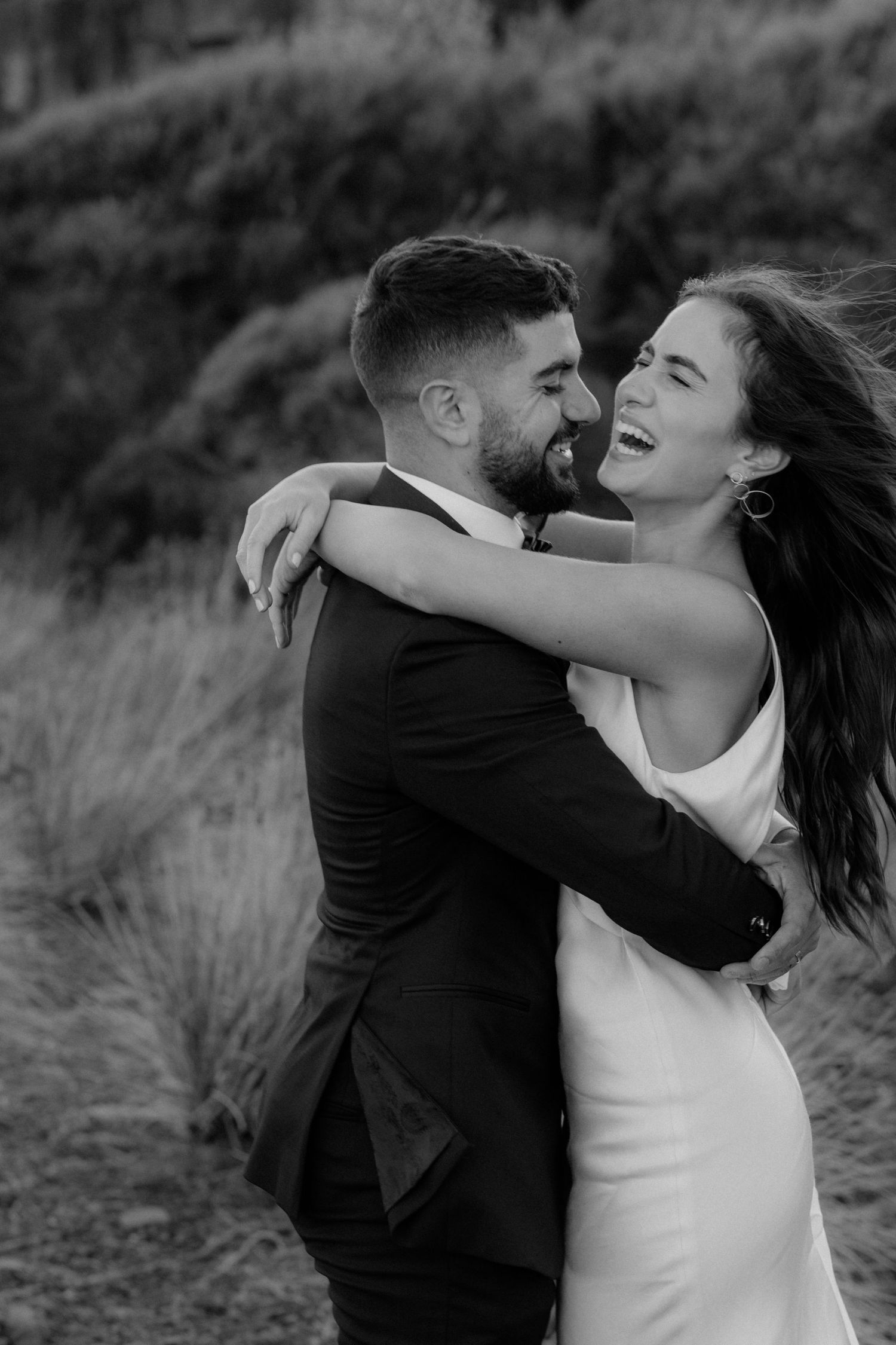 Joyful black and white portrait of wedding couple embracing outdoors.