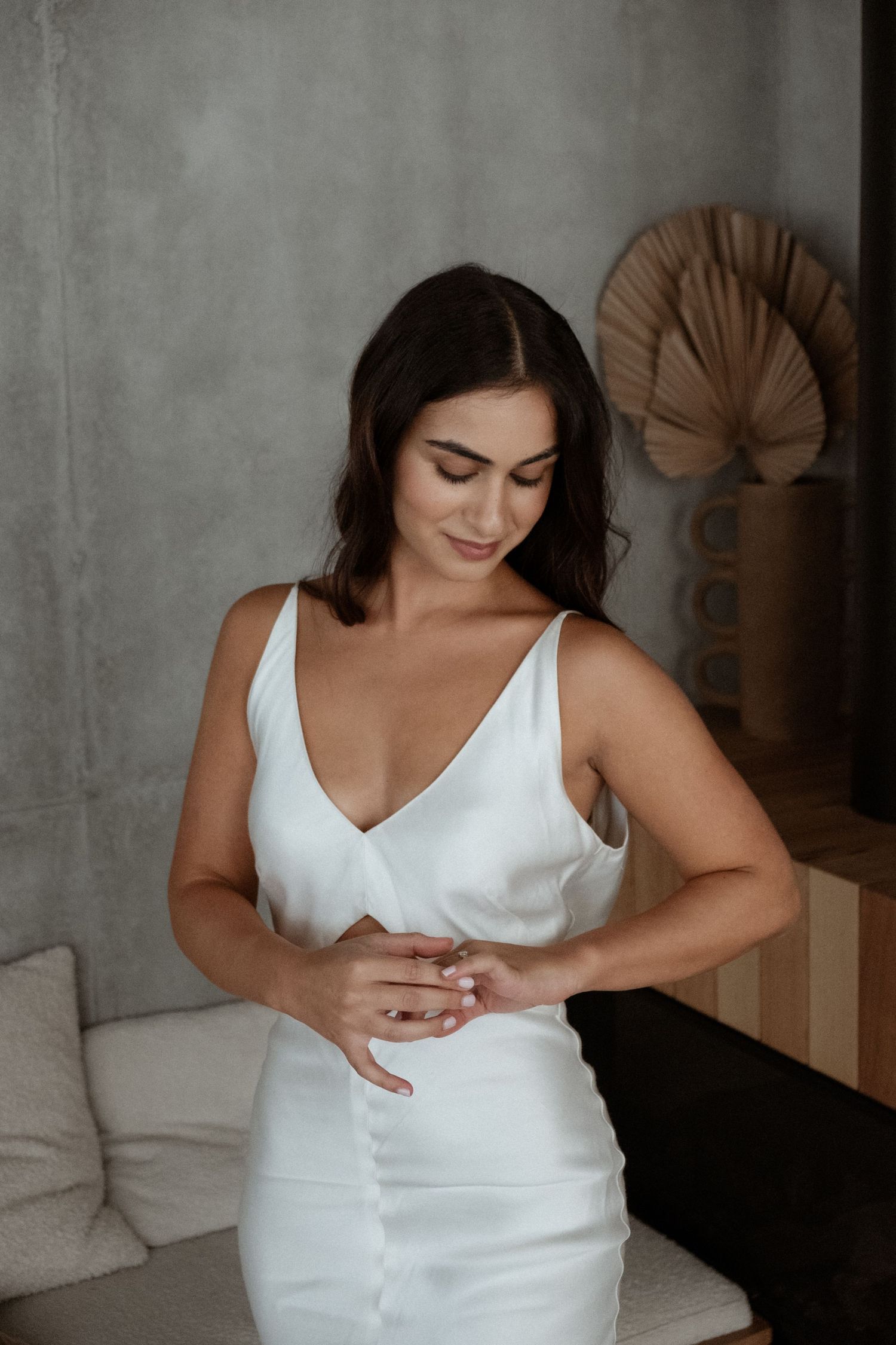 Woman in elegant white dress standing in front of a modern minimalist interior.