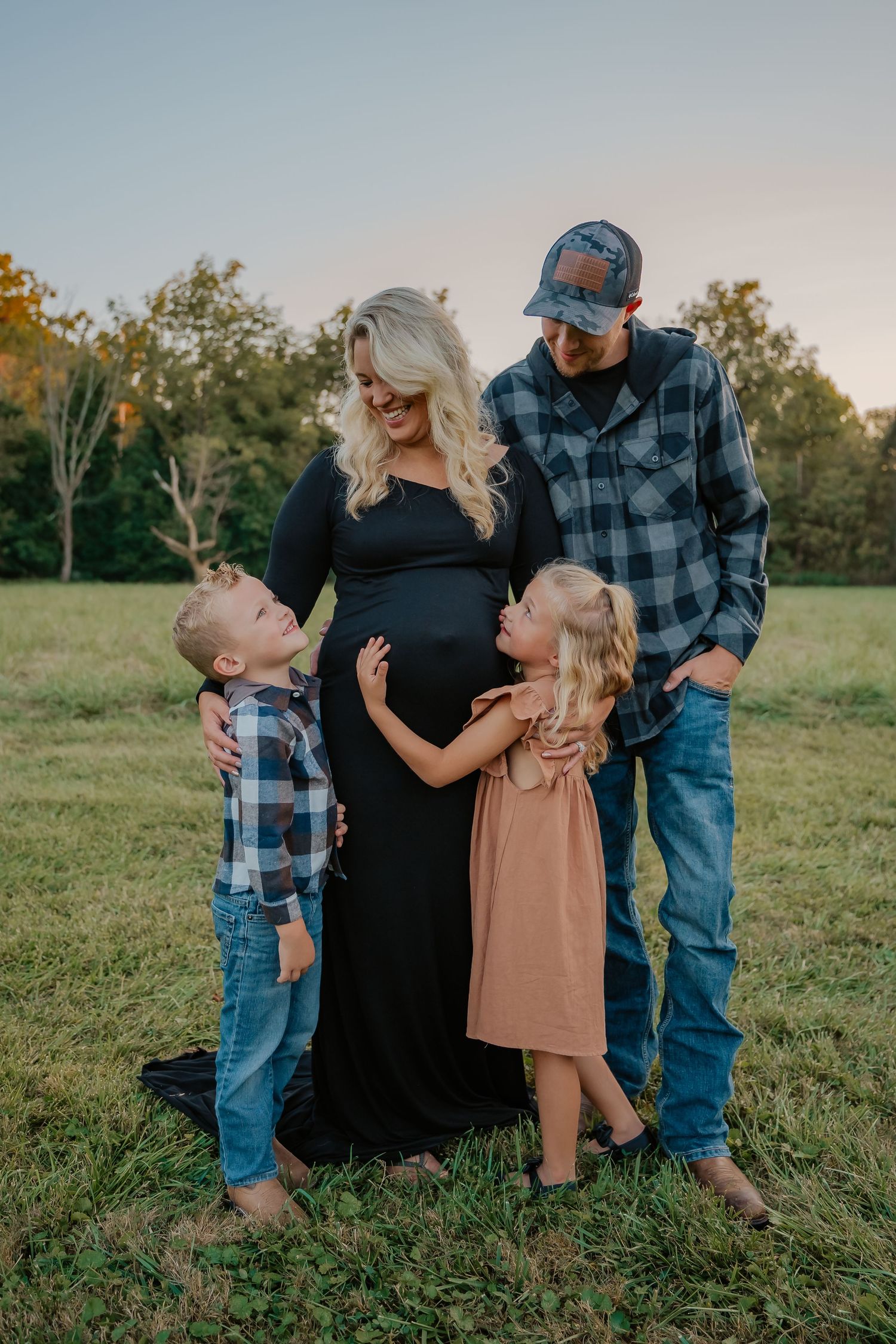 family photo of candid love between two children, mother with baby bump, and father, in a field for a maternity photo session Harrison Ohio.