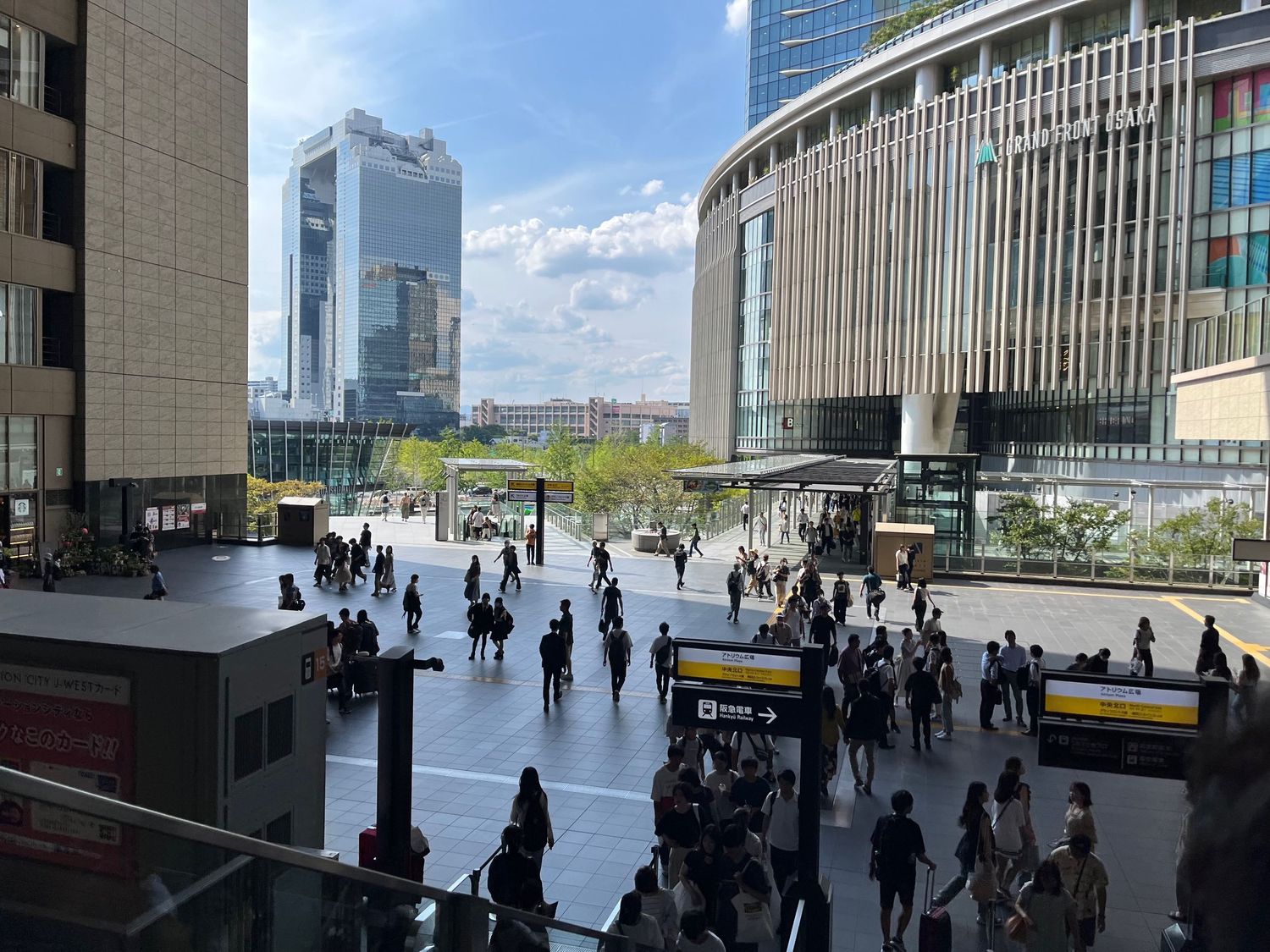 Modern urban plaza with people walking between office buildings in Japan.
