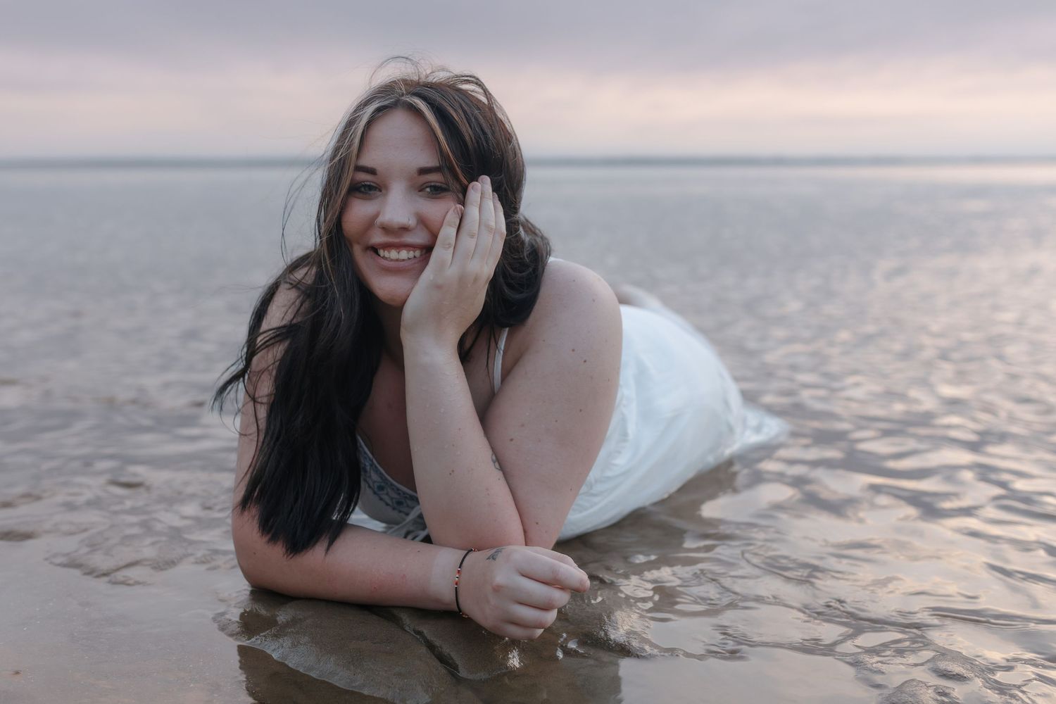 High school senior laying in Lake Sakakawea during golden hour at Government Bay near Garrison North Dakota senior photography session