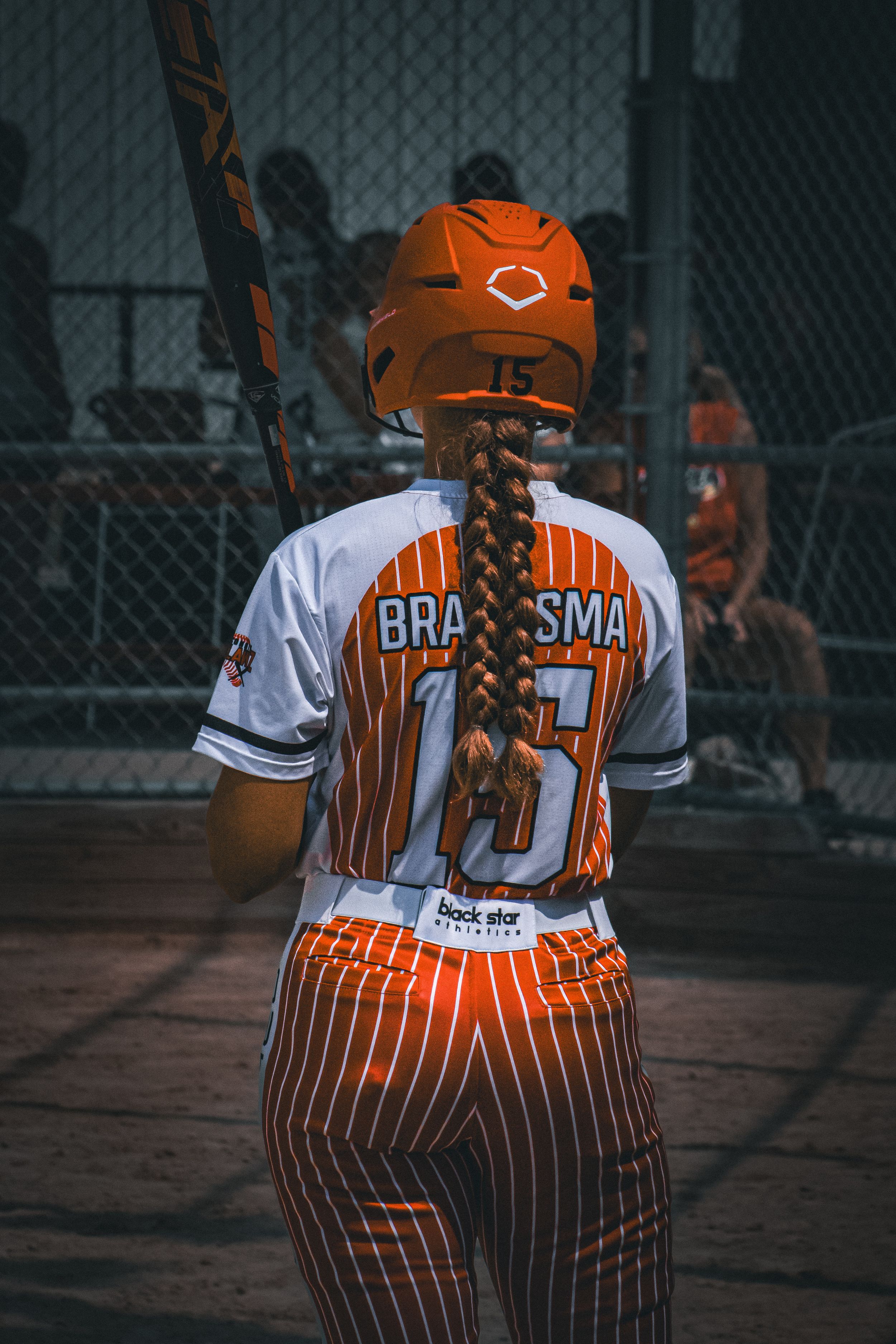 Softball player posed away from camera in uniform and helmet