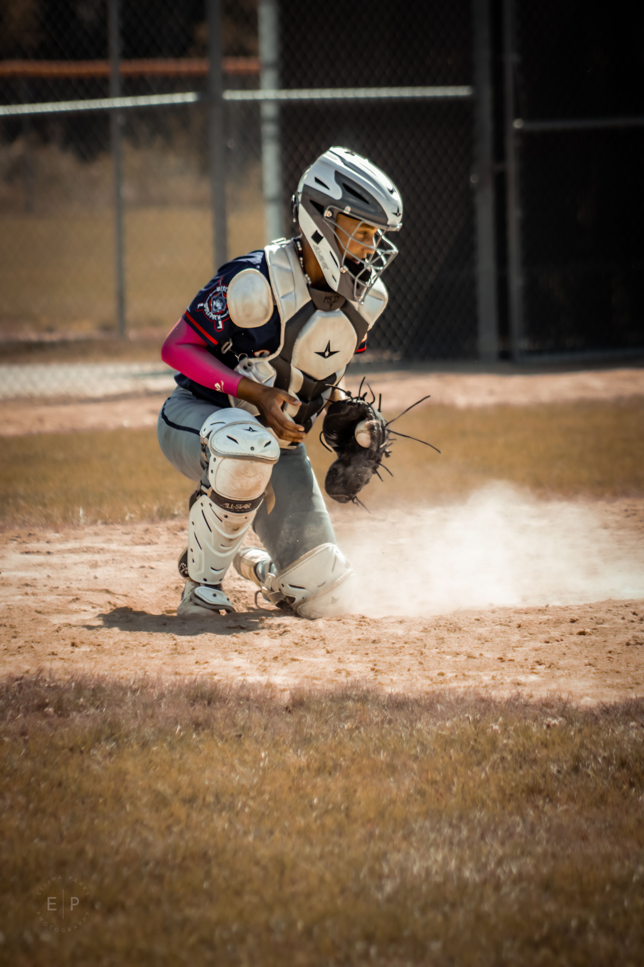 Baseball catcher crouched in position on home plate, waiting for runner