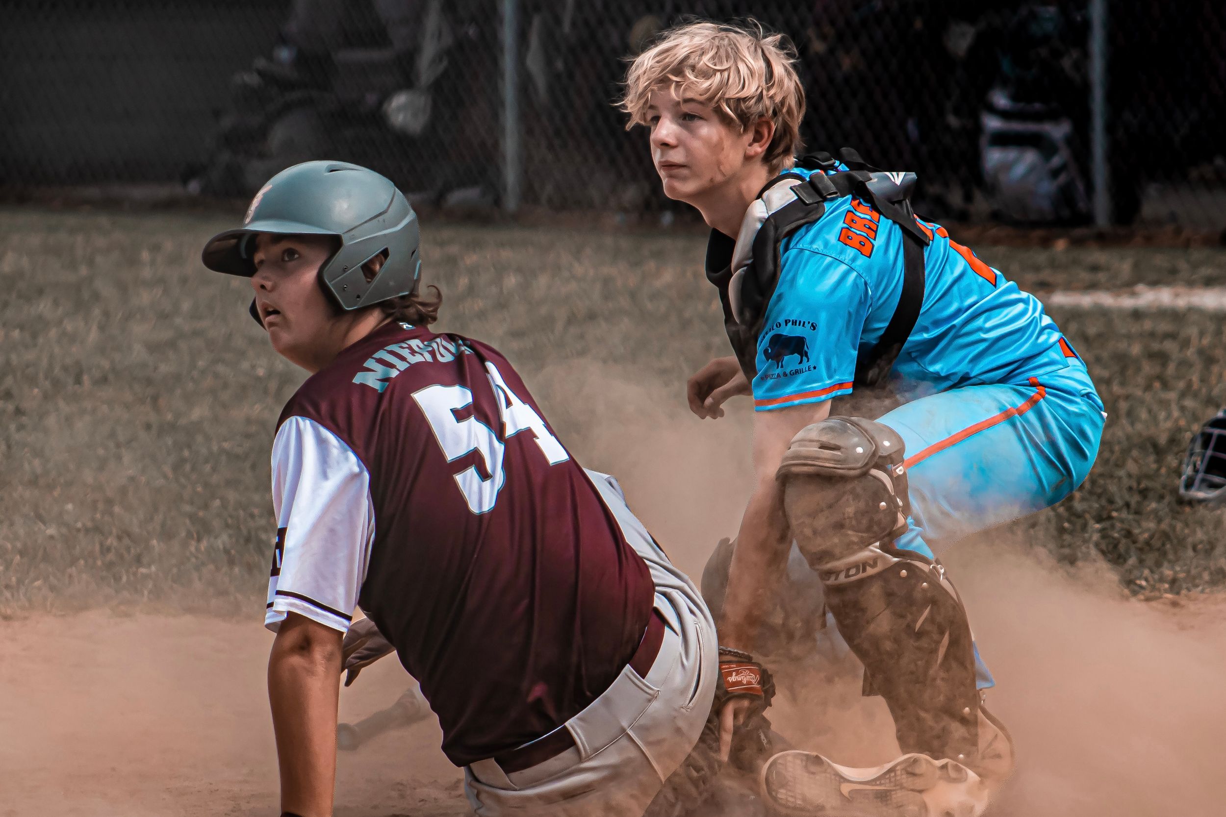 Baseball catcher awaiting umpire's call on a tag out with opposing player at home plate.