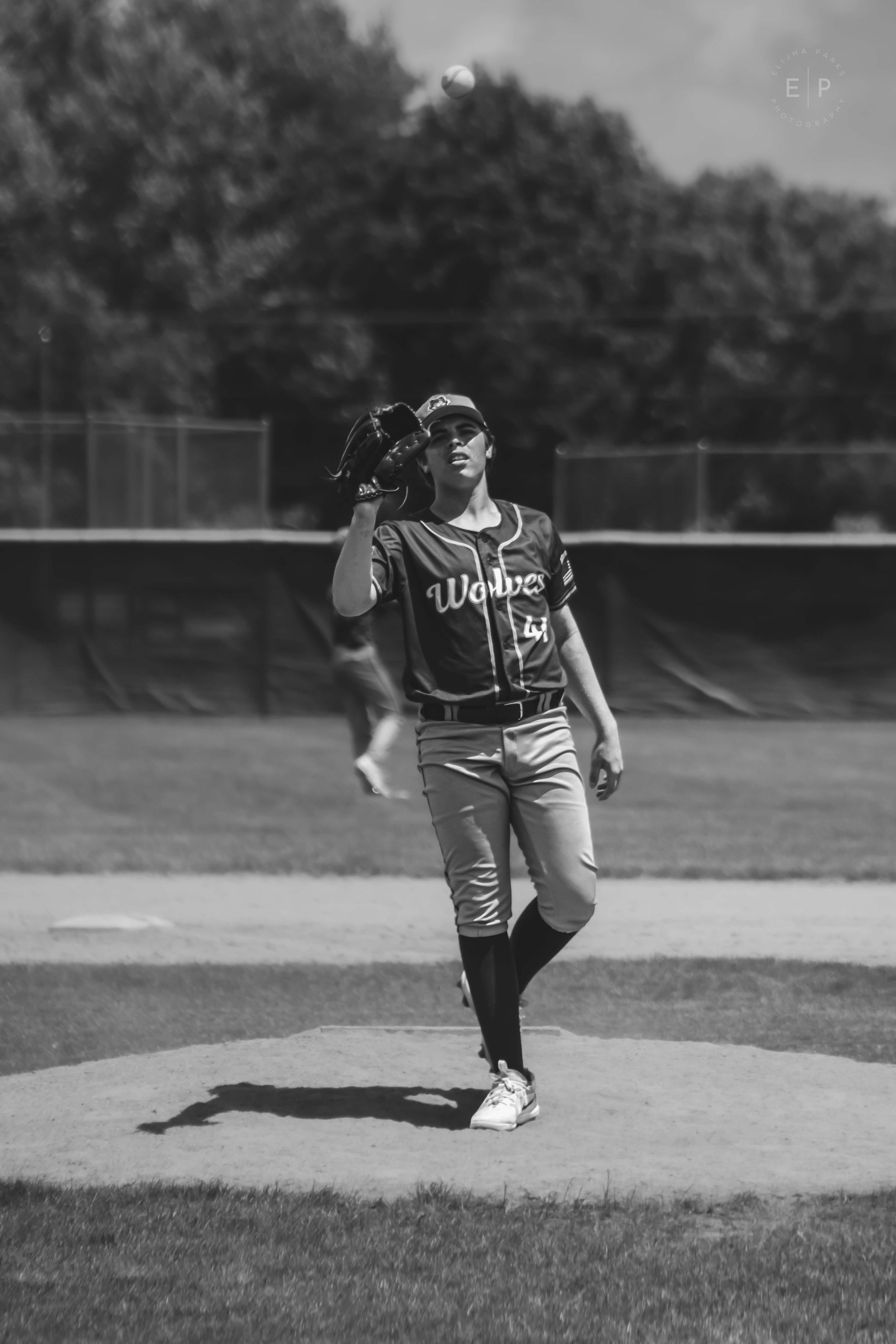 Baseball pitcher on mound with glove up waiting for ball to be thrown to him