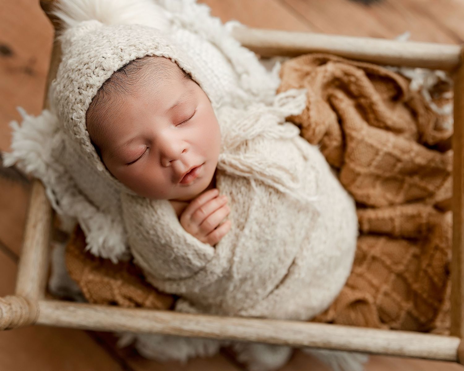 Peaceful sleeping baby wrapped in green knit blanket.