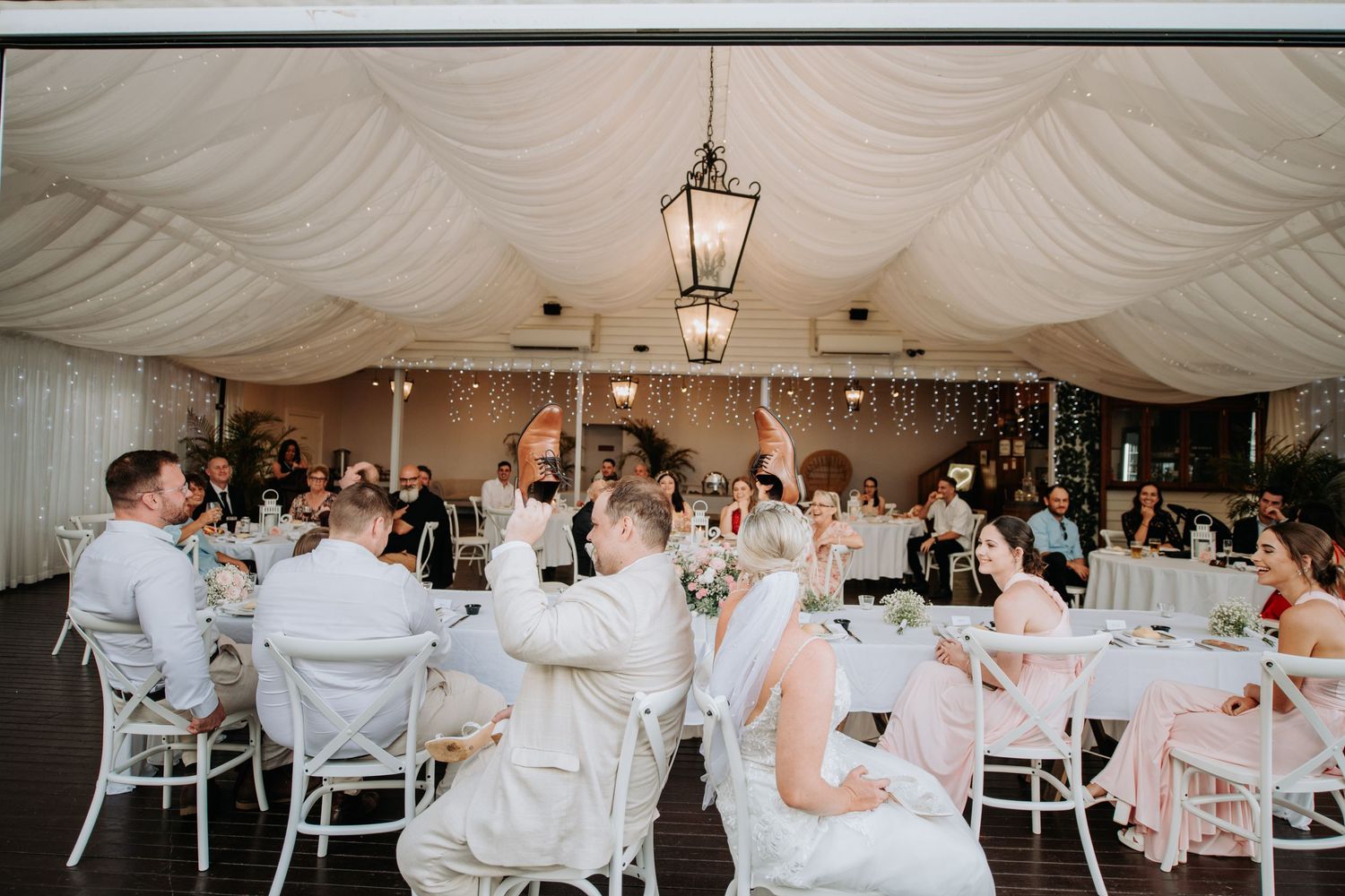 Reception tent with elegant lantern lighting and white table settings.