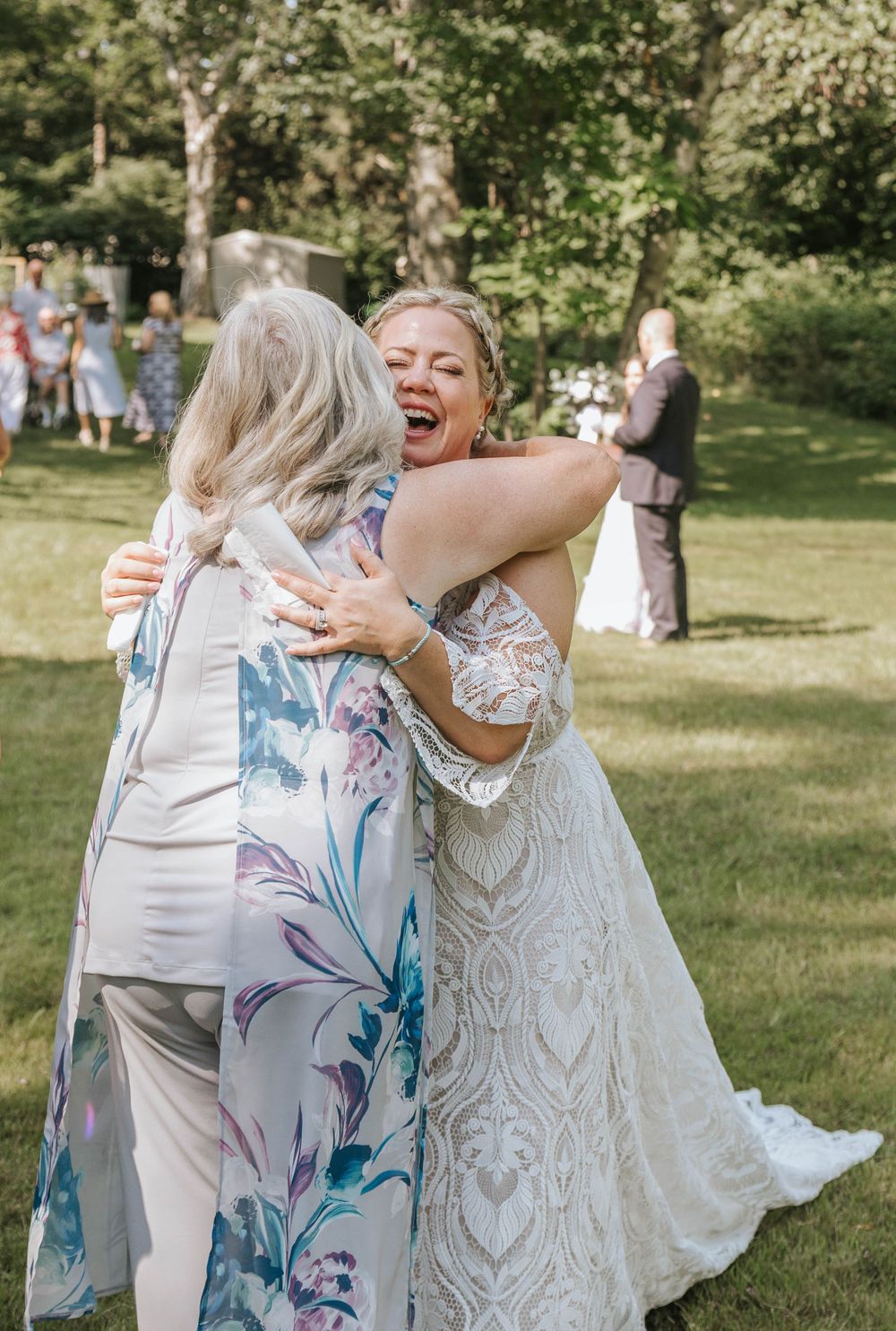 Wedding guests celebrate with dancing and hugs on a sunny lawn.