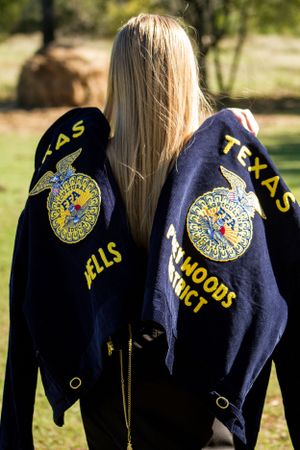 Two FFA jackets displaying Texas chapters logos hanging against a rural background.