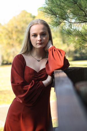 Artistic portrait series showing poses in a red dress against natural outdoor lighting.