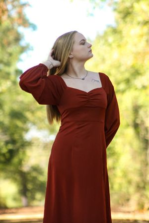 Fashion photoshoot in a forest setting featuring a burgundy dress with dramatic poses.