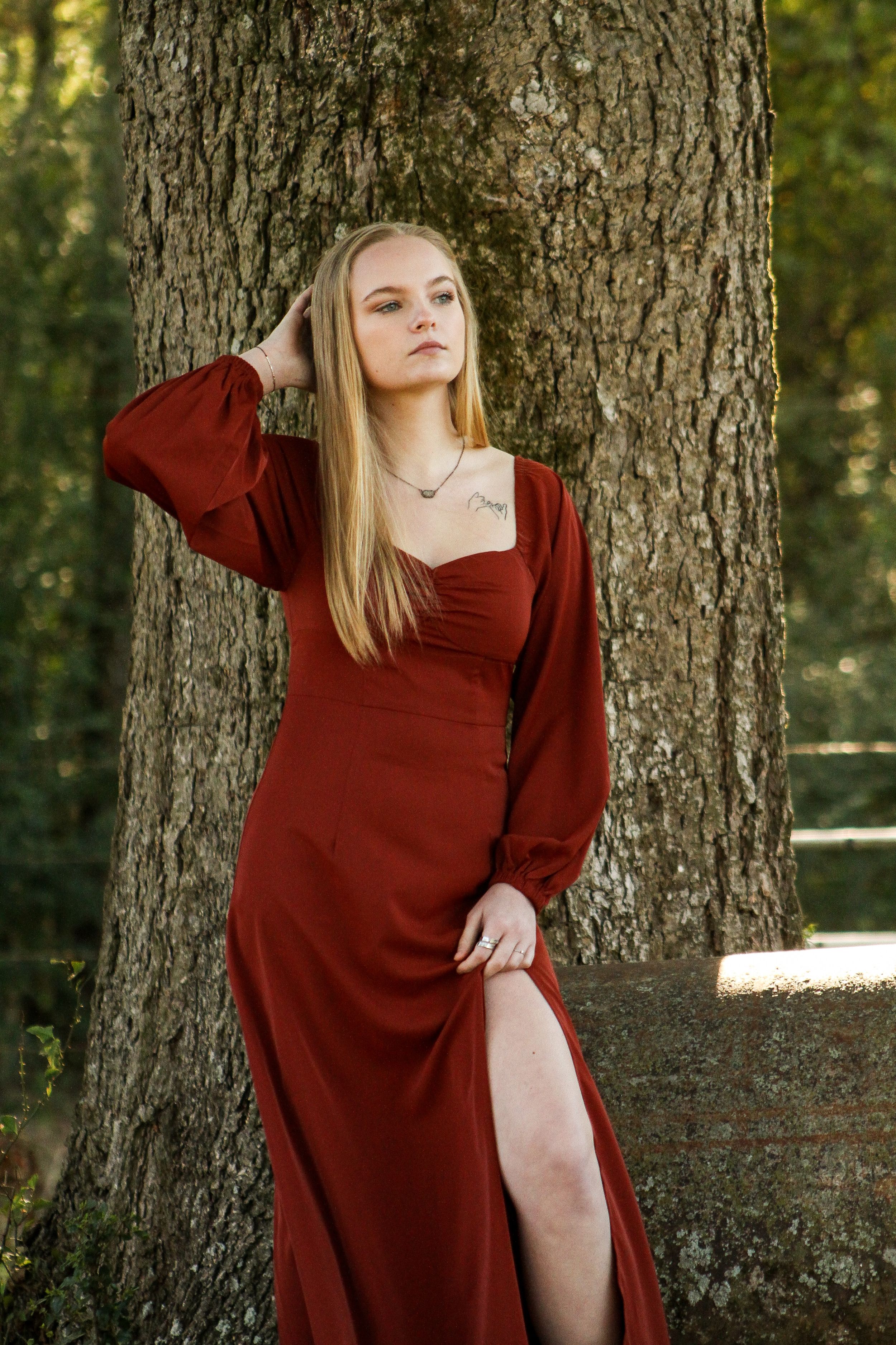 Outdoor fashion photography session featuring poses against a large tree trunk.