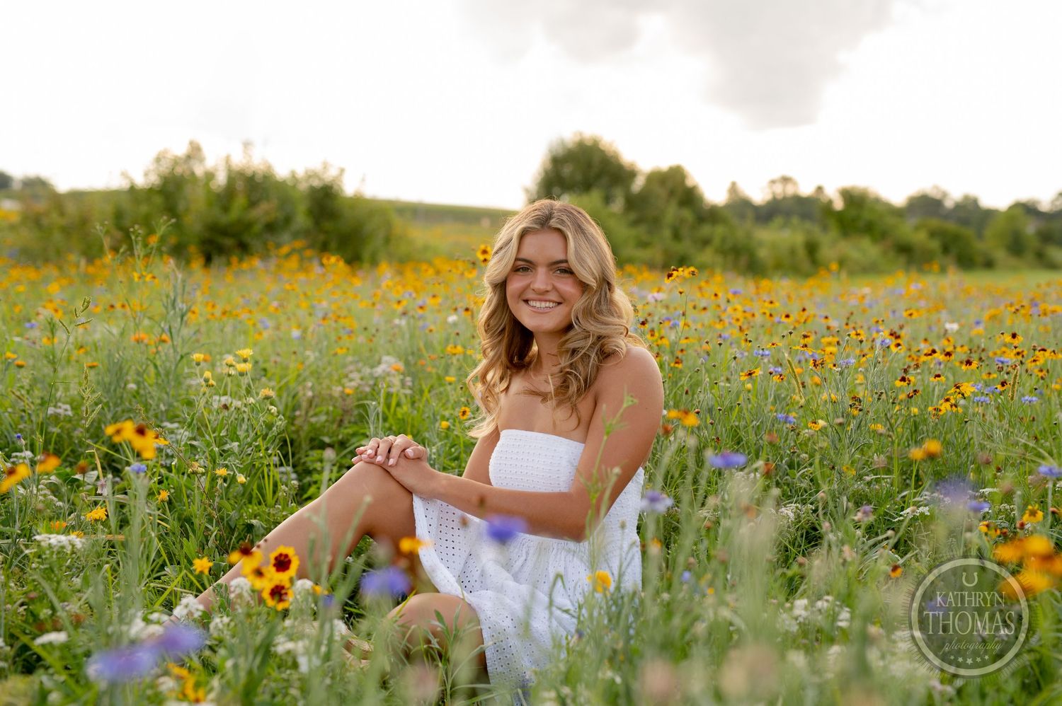 A summertime portrait of someone relaxing in a field filled with yellow sunflowers and greenery.