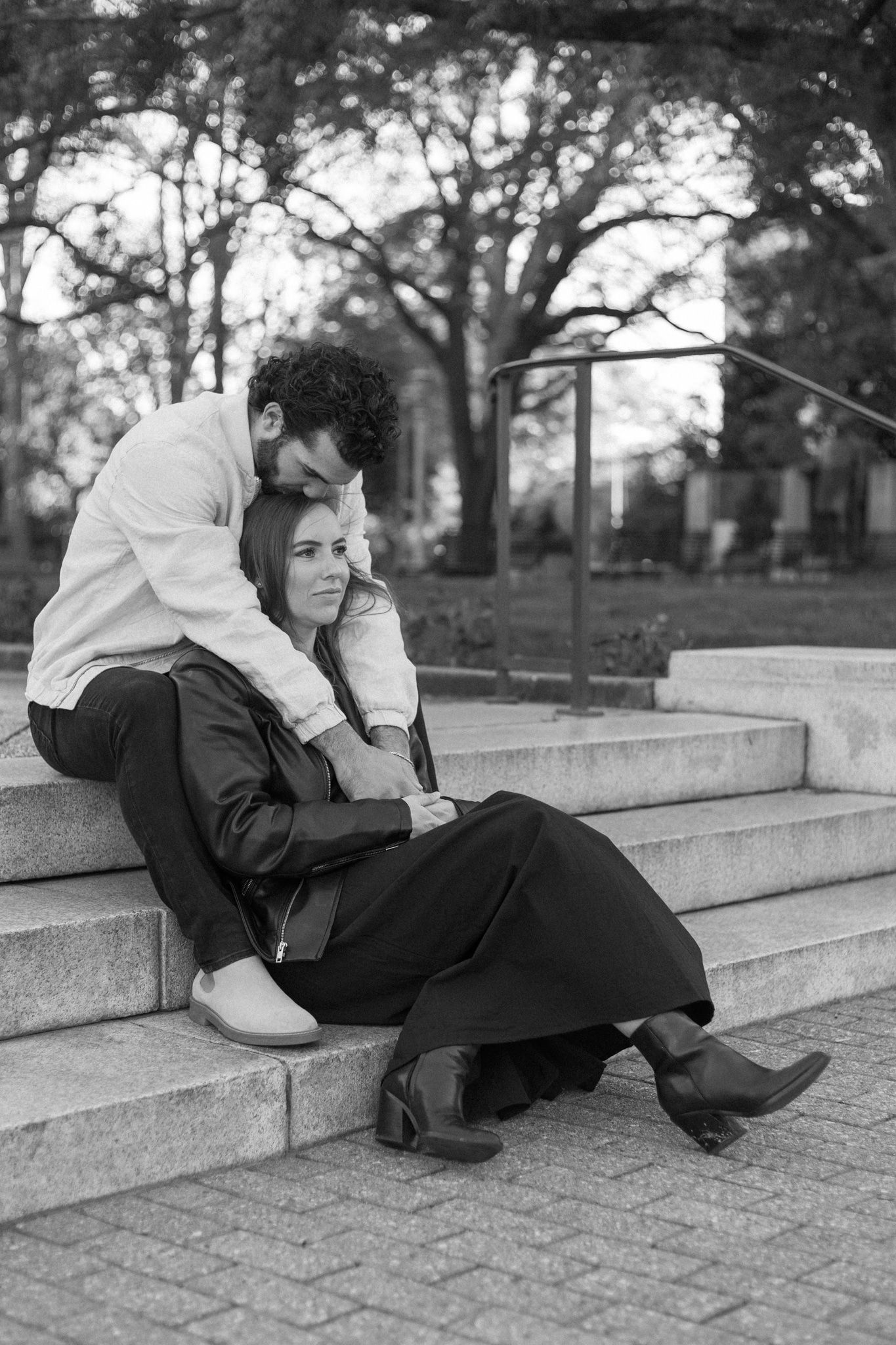 Black and white. Man holds his girlfriend and kisses her forehead.