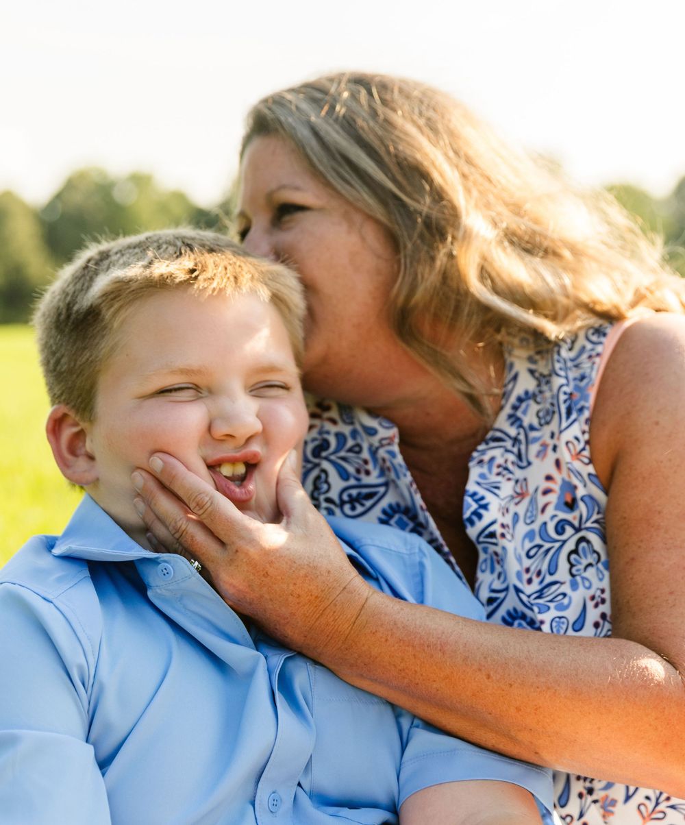 A playful outdoor family photo showing affectionate interaction in golden sunlight.