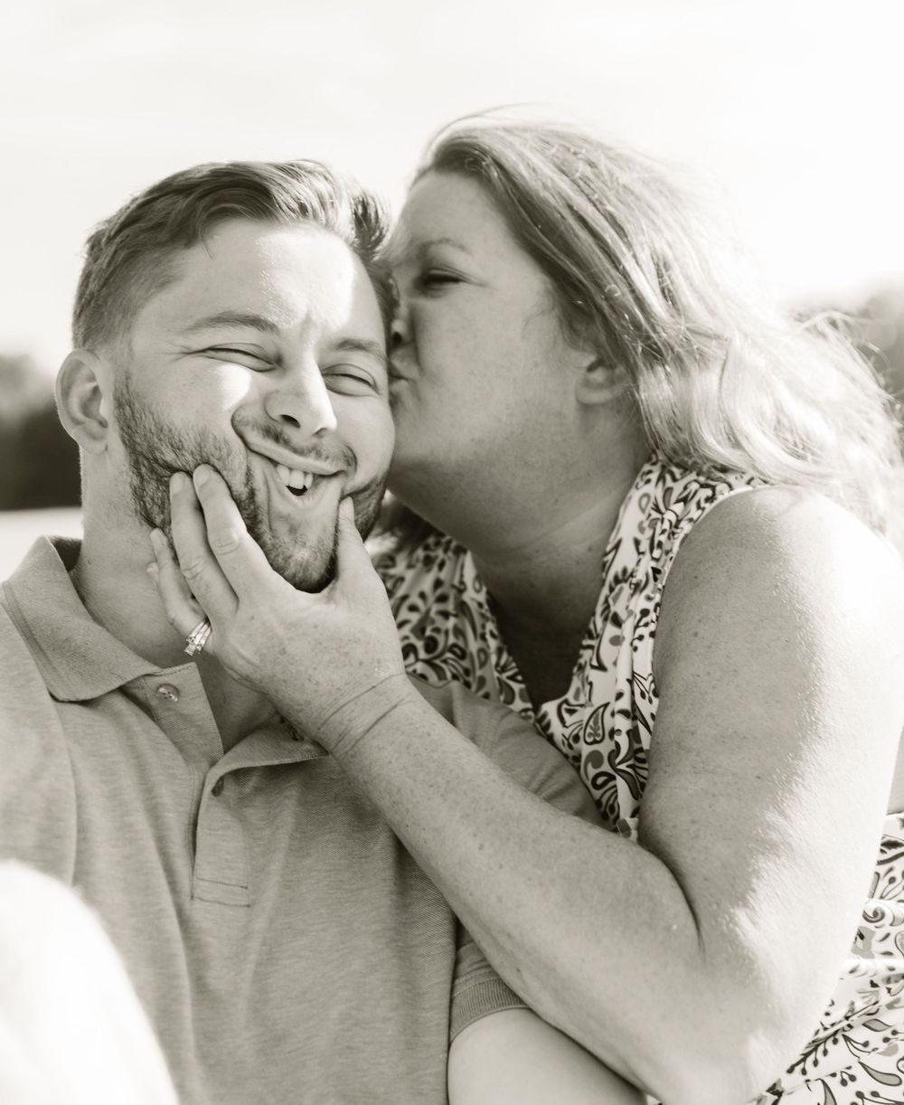 A black and white portrait capturing a playful moment of family affection.