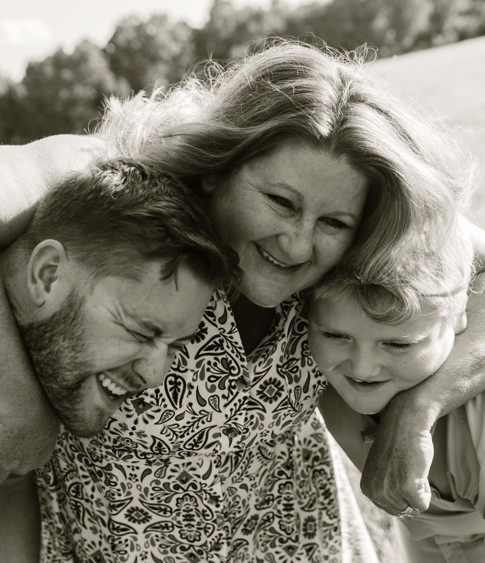 A joyful black and white portrait of three people sharing a candid laugh together outdoors.