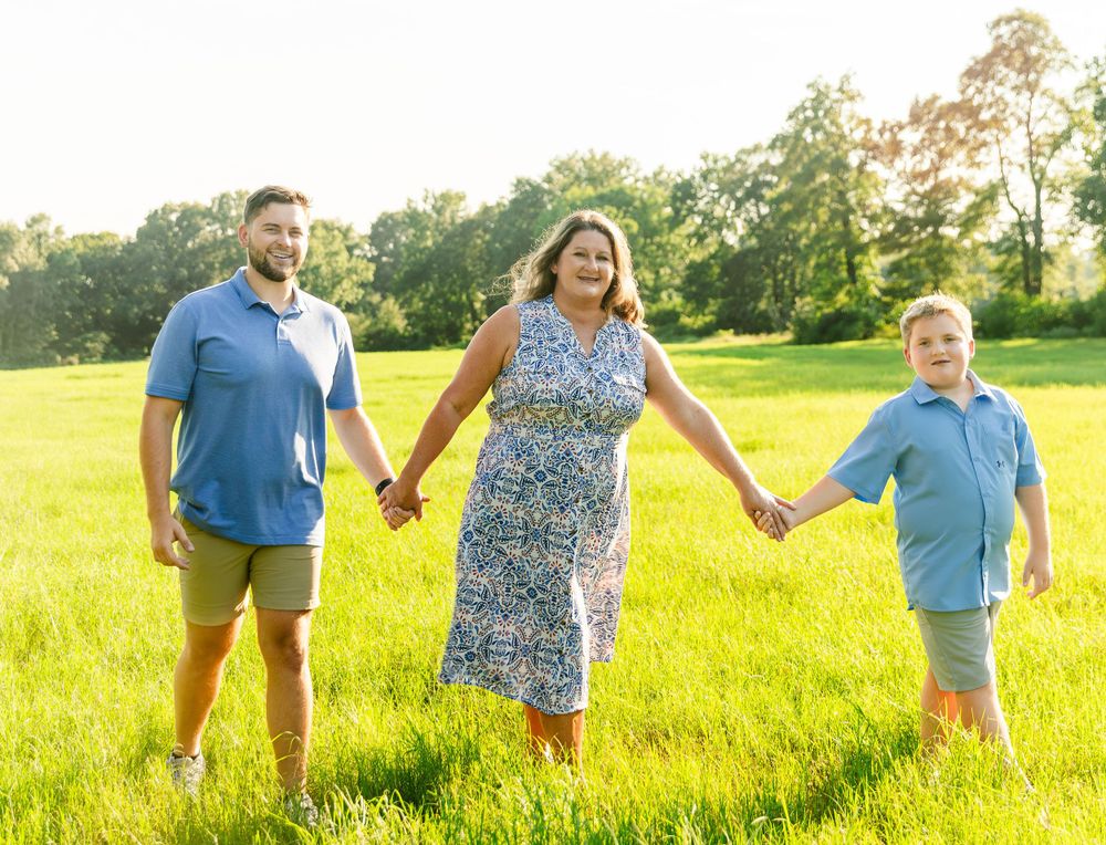 A family walks hand in hand through a sun-drenched summer meadow.