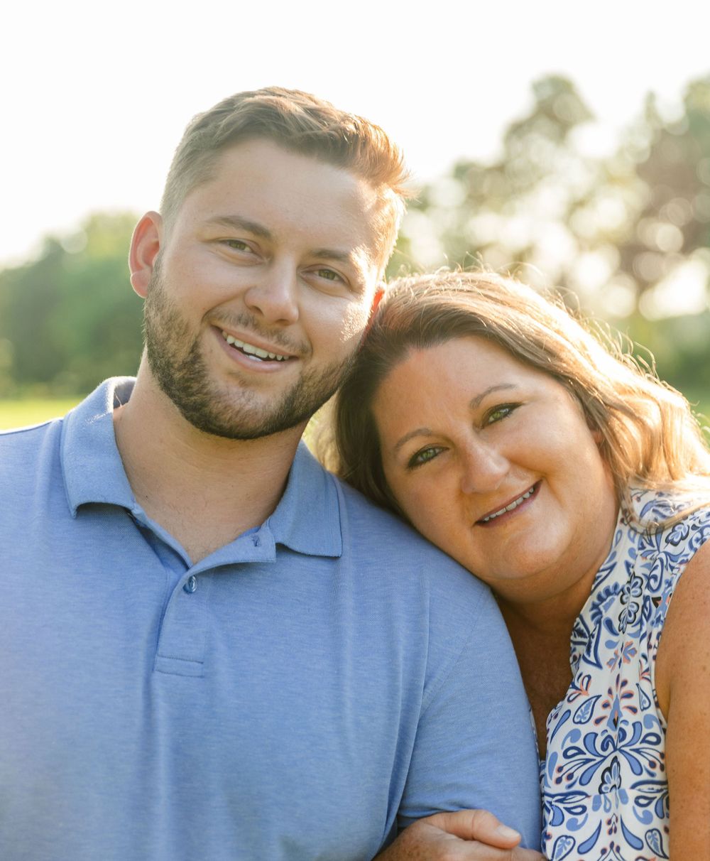 A couple in blue and floral print poses together in golden evening light.
