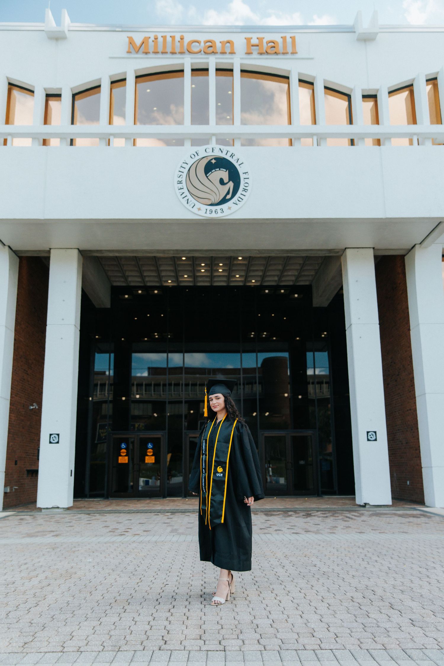 Graduation photos taken in front of Millican Hall showing academic achievement in black cap and gown.