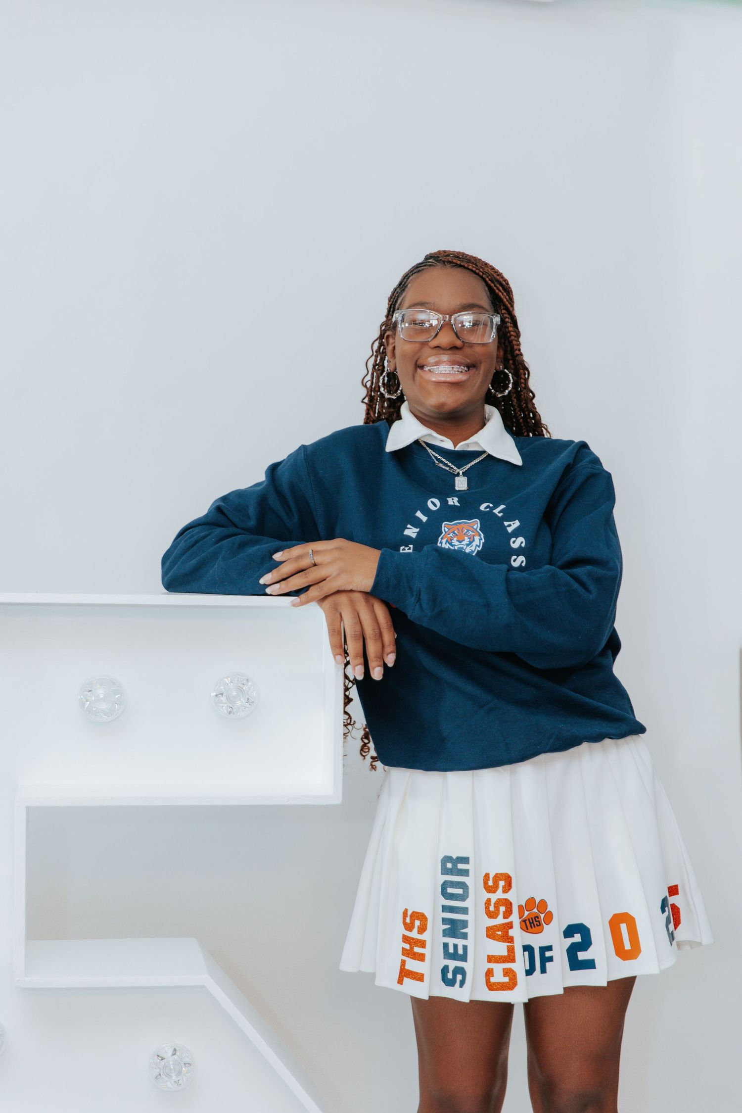 A series of cheerful poses in a navy uniform and white skirt against a light background.