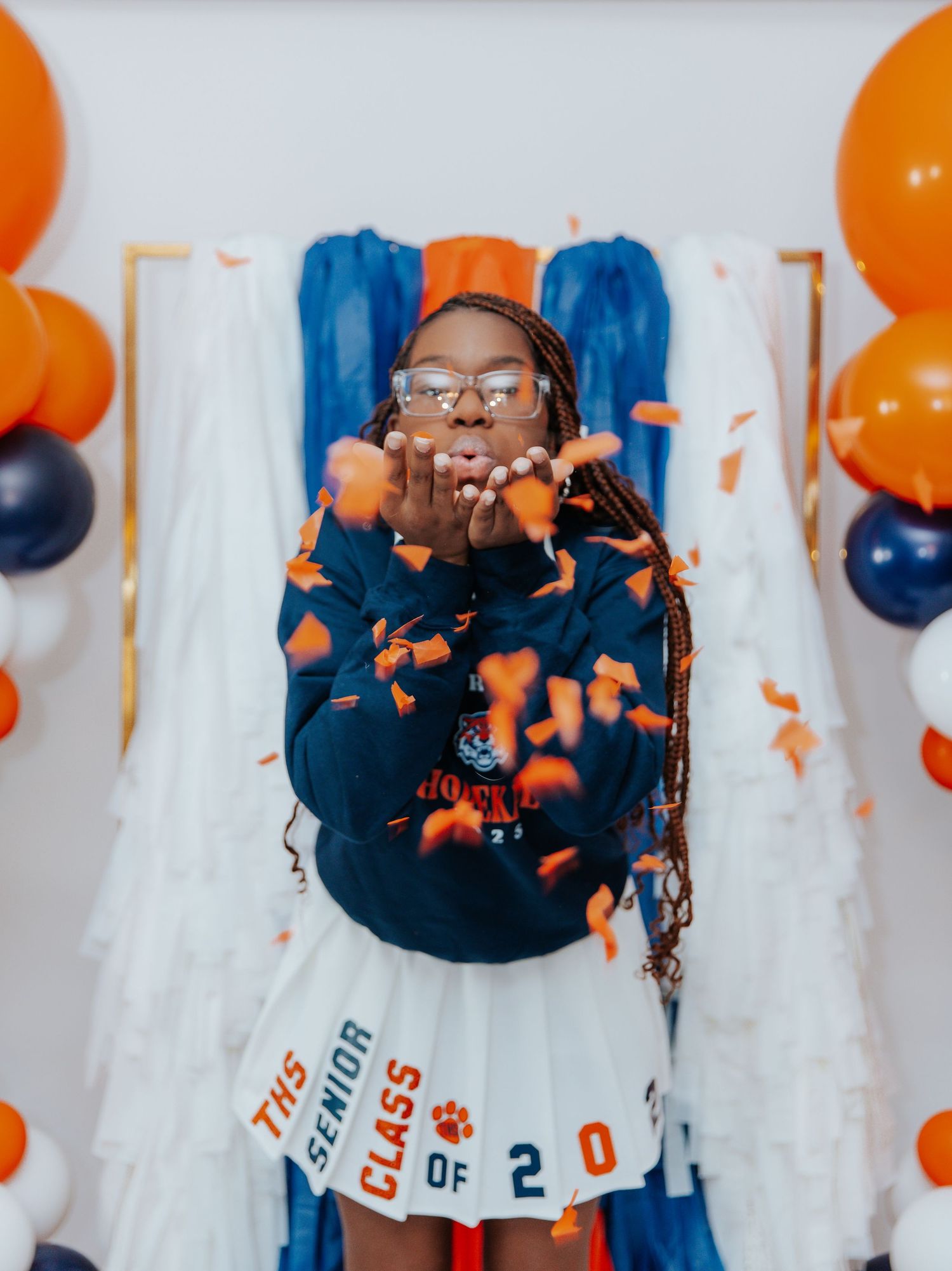 A celebratory scene with orange and blue balloons against a white backdrop.