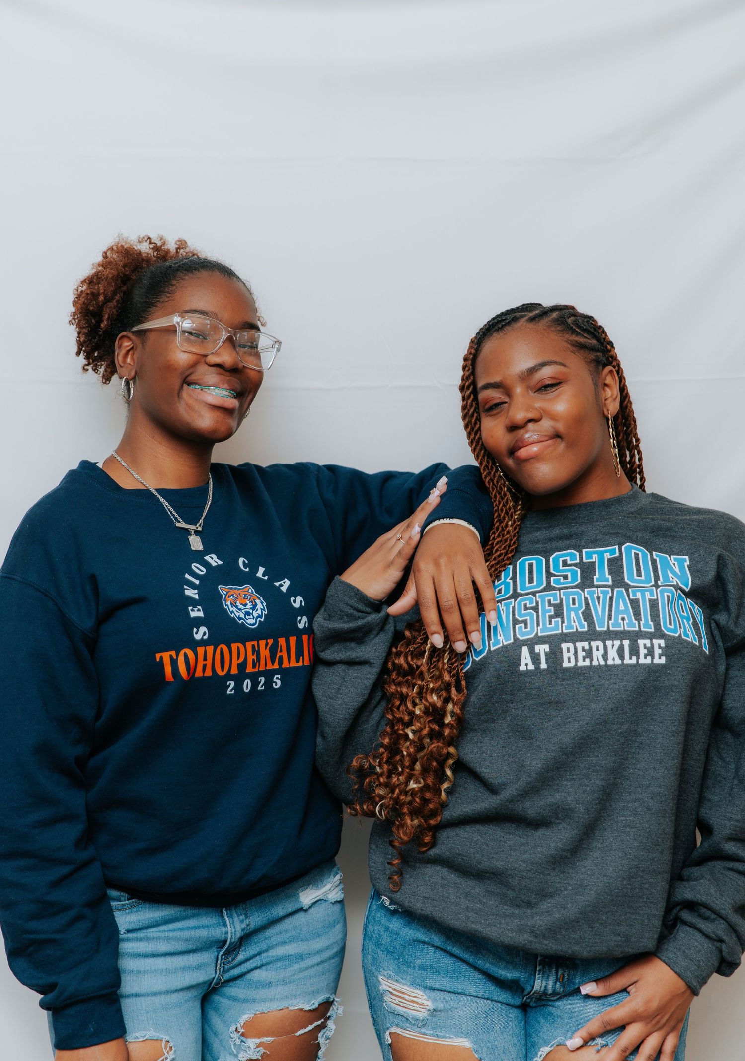 Two students wearing university sweatshirts pose together against white background.