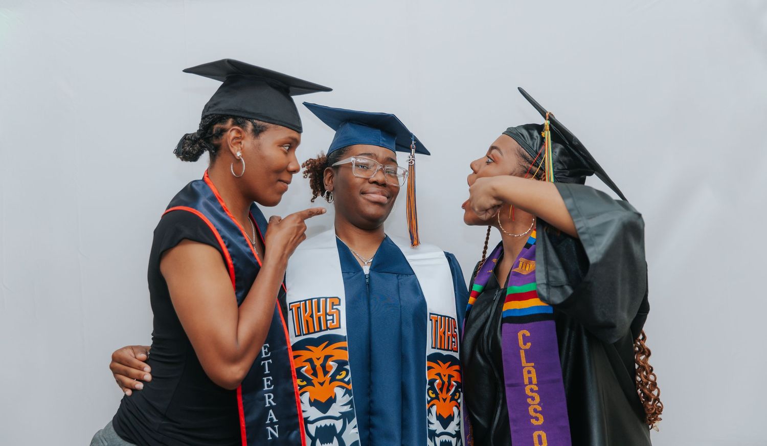 Graduates in caps and gowns celebrating with university stoles and tassels.