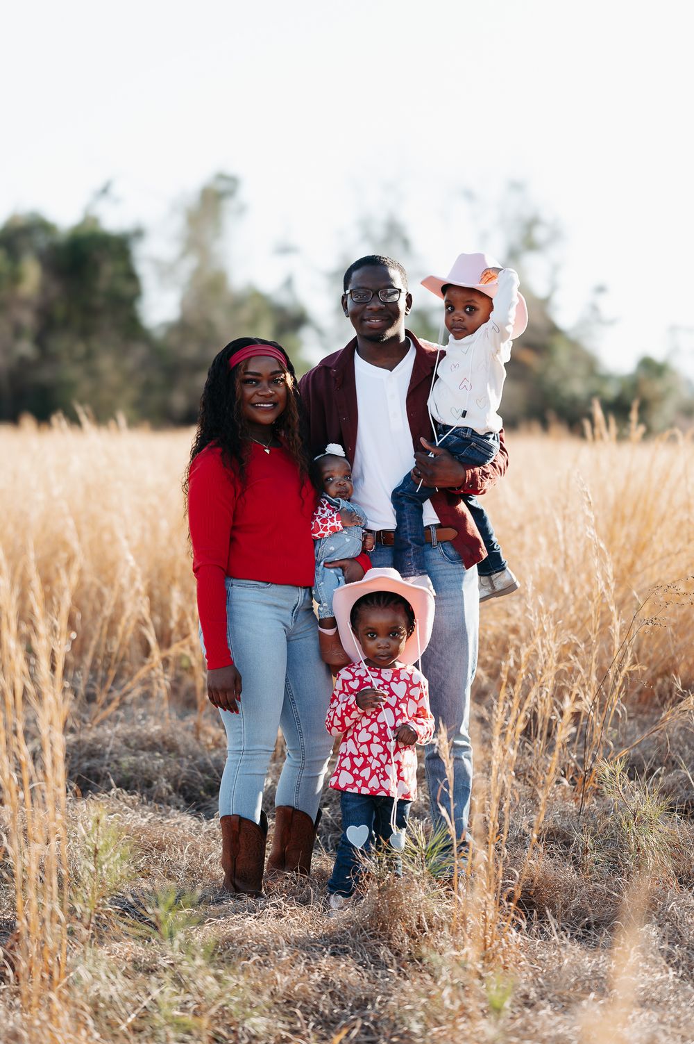 A group standing together in a golden field during sunset wearing casual clothing and smiling at the camera.