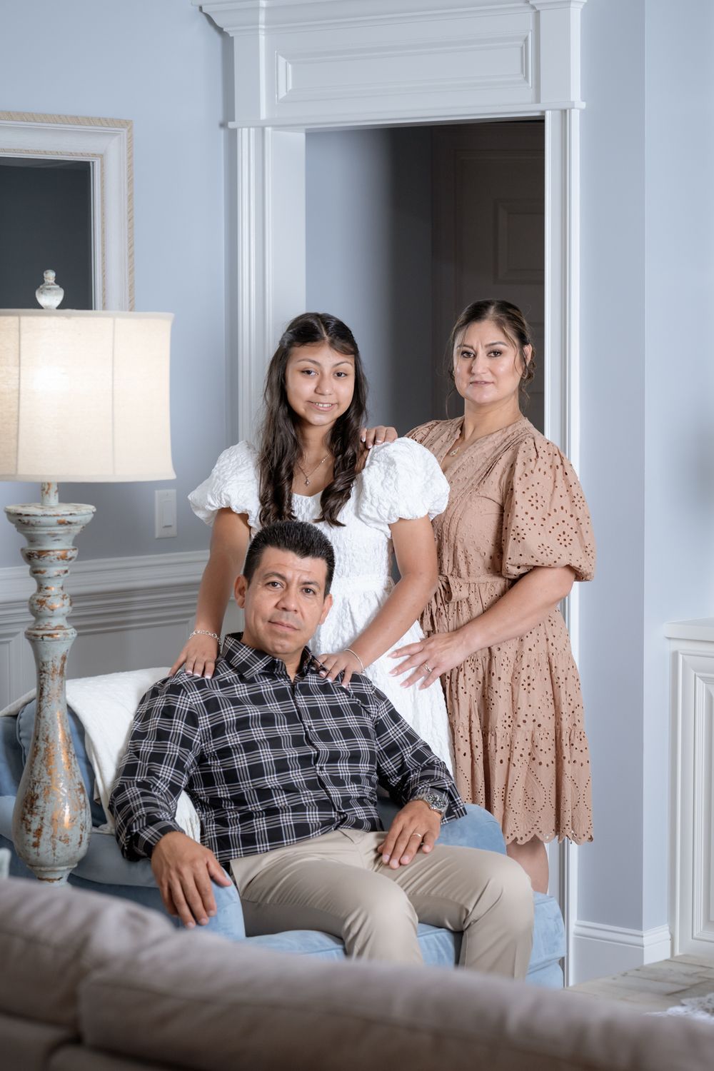 A family poses together in an elegant living room with classic molding and decor.
