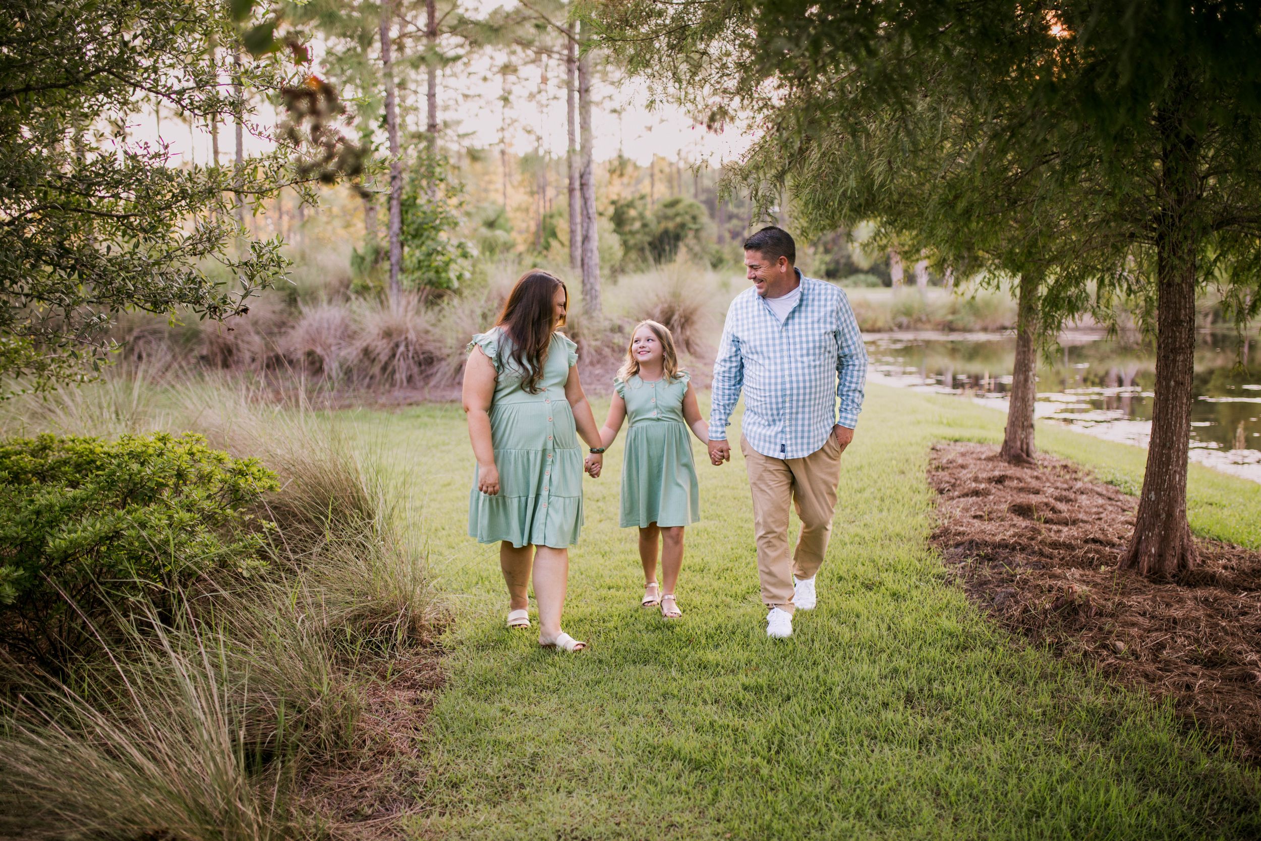 Family walking hand in hand through park wearing coordinating blue and mint green outfits.